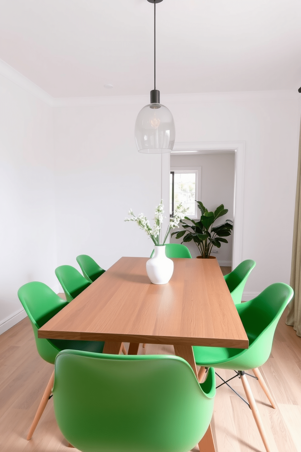 A contemporary dining room featuring modern green chairs with sleek lines around a minimalist wooden table. The walls are painted in a soft white, enhancing the fresh and vibrant look of the green chairs, while a statement pendant light hangs above the table, adding a touch of elegance.