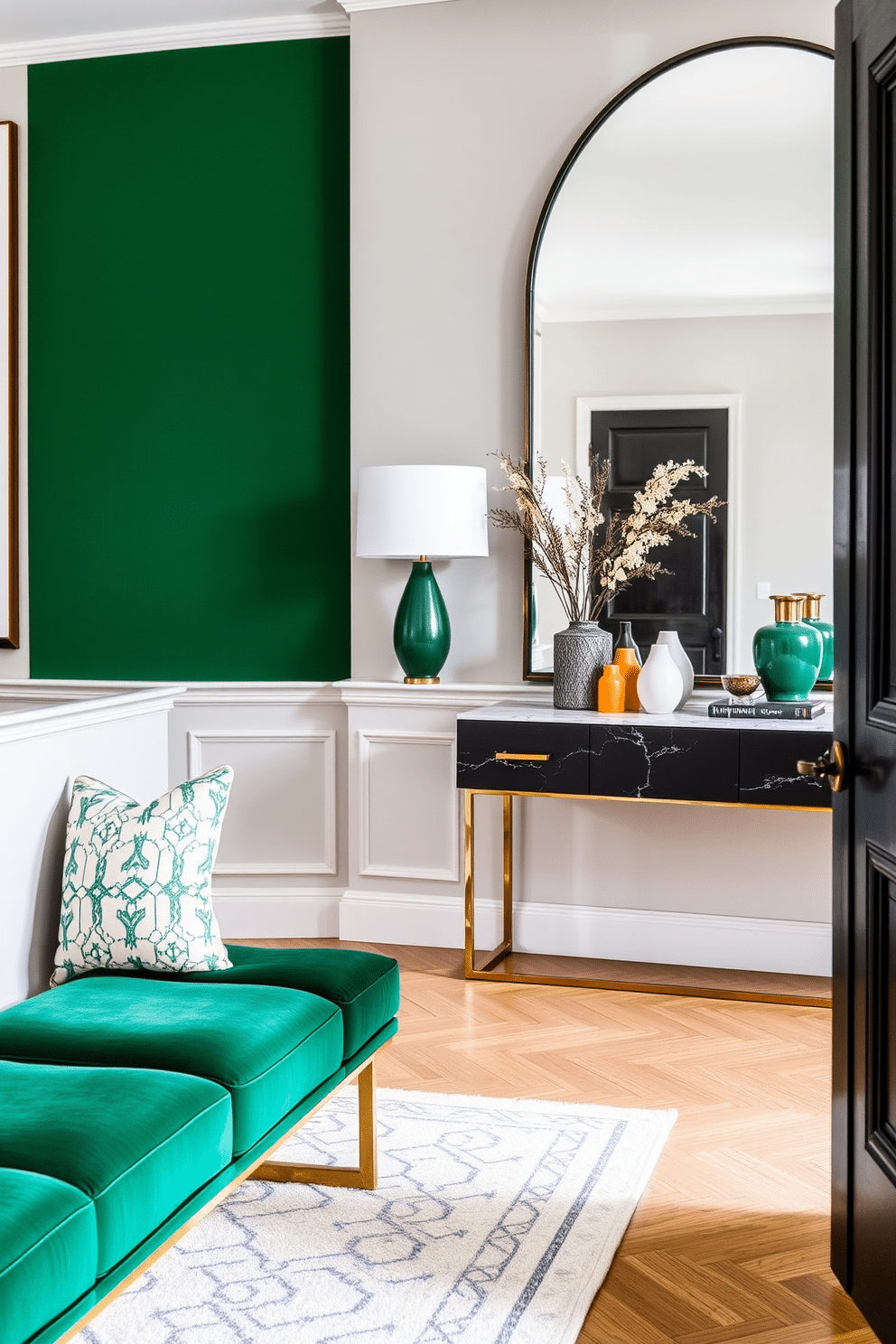 A chic green bench is positioned against the wall in the seating area, upholstered in a rich emerald fabric that adds a pop of color. The bench features sleek gold legs, complementing the modern aesthetic of the space. The foyer is designed with a harmonious blend of light and dark tones, featuring a statement green accent wall that invites guests in. A stylish console table with a marble top is adorned with decorative objects and a large mirror that enhances the sense of space.