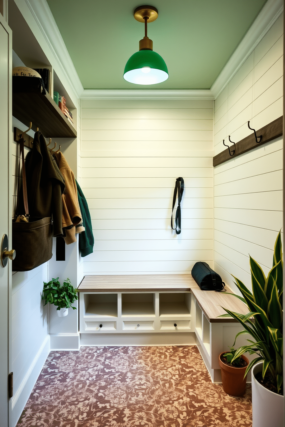 A welcoming mudroom features soft green lighting fixtures that create a warm and inviting ambiance. The walls are adorned with shiplap in a light hue, and a built-in bench with storage cubbies provides a functional yet stylish element. The floor is covered with durable, patterned tiles that add visual interest while being easy to clean. Potted plants in the corners enhance the fresh feel of the space, complemented by hooks for coats and bags in a brushed brass finish.