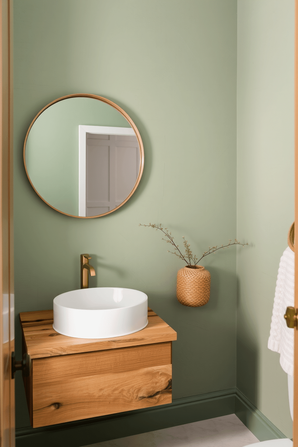 A serene powder room enveloped in soft green hues, featuring textured walls that evoke a sense of calm. The space is adorned with natural elements, including a reclaimed wood vanity topped with a sleek white sink and a brushed gold faucet. A large round mirror with a minimalist frame reflects the tranquil ambiance, while a woven basket sits in the corner, adding warmth. Delicate greenery is placed on the countertop, enhancing the connection to nature and creating a refreshing atmosphere.