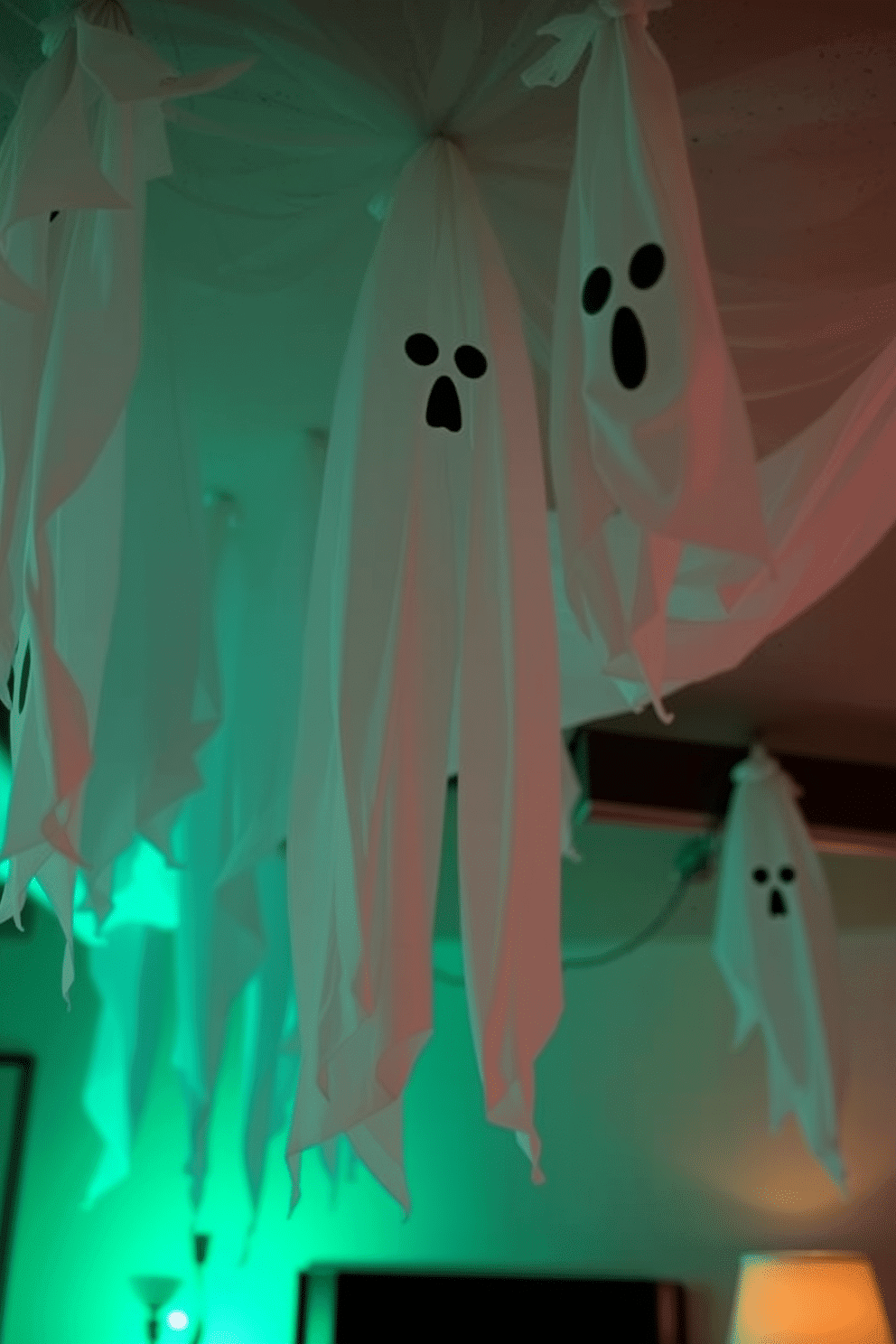 Create a spooky Halloween basement atmosphere featuring hanging ghosts made from white sheets. The ghosts should be suspended from the ceiling, gently swaying in the dim light, creating an eerie effect throughout the space.