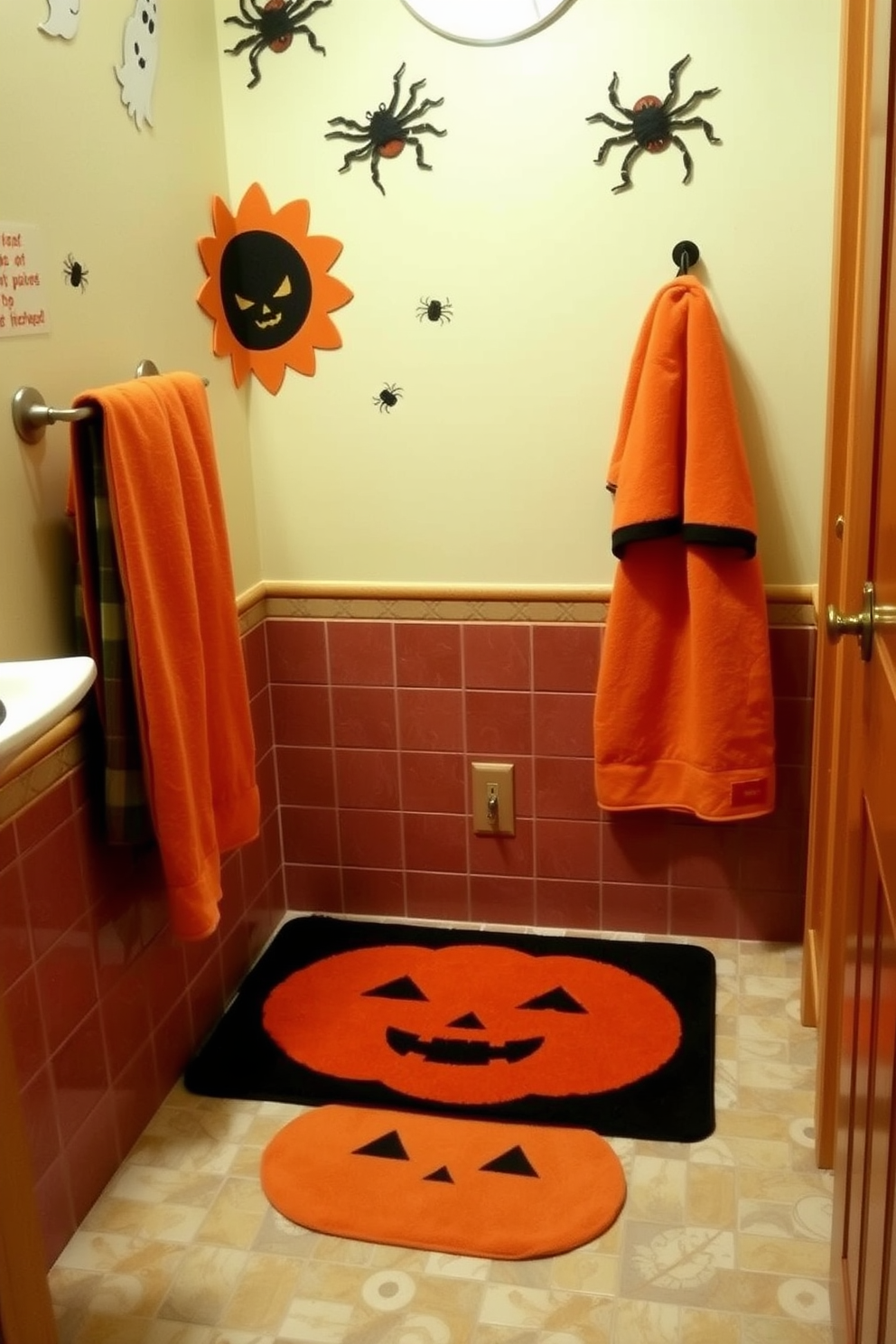 A whimsical bathroom setting featuring a pumpkin-themed bath mat and matching towels. The walls are adorned with playful Halloween decorations, including ghost and spider motifs, creating a festive atmosphere.