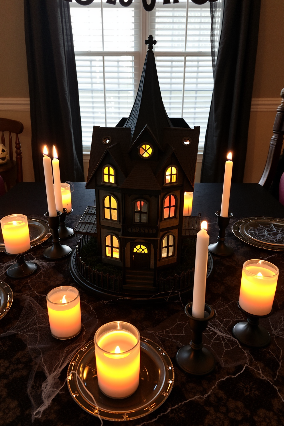 A miniature haunted house sits as the centerpiece on the dining table, surrounded by flickering LED candles that cast eerie shadows. The table is adorned with black lace tablecloth and scattered faux spider webs, creating a spooky yet inviting atmosphere for Halloween.