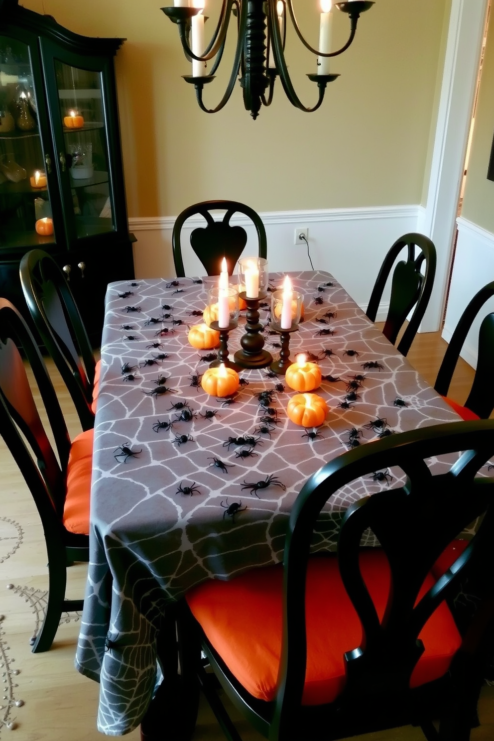 A whimsical dining room setting for Halloween. The table is dressed with a spiderweb tablecloth adorned with plastic spiders scattered throughout. Surrounding the table are elegant black chairs with orange cushions. Flickering candlelight from pumpkin-shaped candles adds a spooky ambiance to the room.