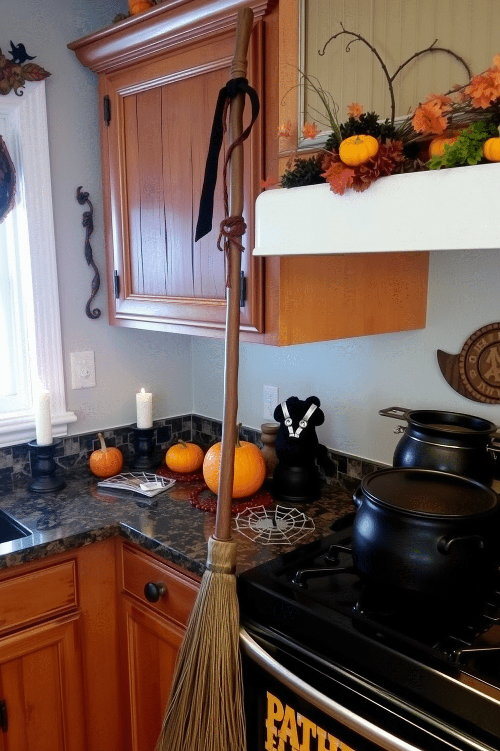 A whimsical kitchen setting featuring a witch's broomstick as a decor accent. The broomstick leans against a rustic wooden cabinet adorned with autumn-themed decorations. The countertops are decorated with small pumpkins and spooky candle holders. A black cauldron sits on the stove, adding a playful touch to the Halloween atmosphere.