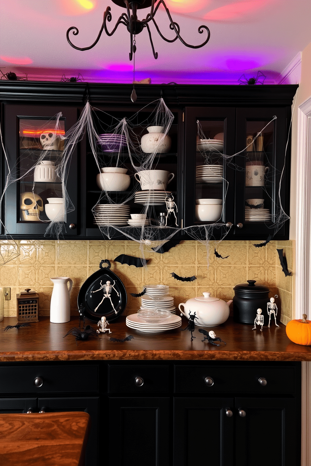 A whimsical Halloween kitchen setting with creepy crawlies adorning the cabinets. Spiders and cobwebs hang from the shelves, while small plastic skeletons and bats are strategically placed among the kitchenware. The cabinets are painted in a deep black color, creating a dramatic backdrop for the decorations. Orange and purple lights flicker above, casting eerie shadows throughout the space.