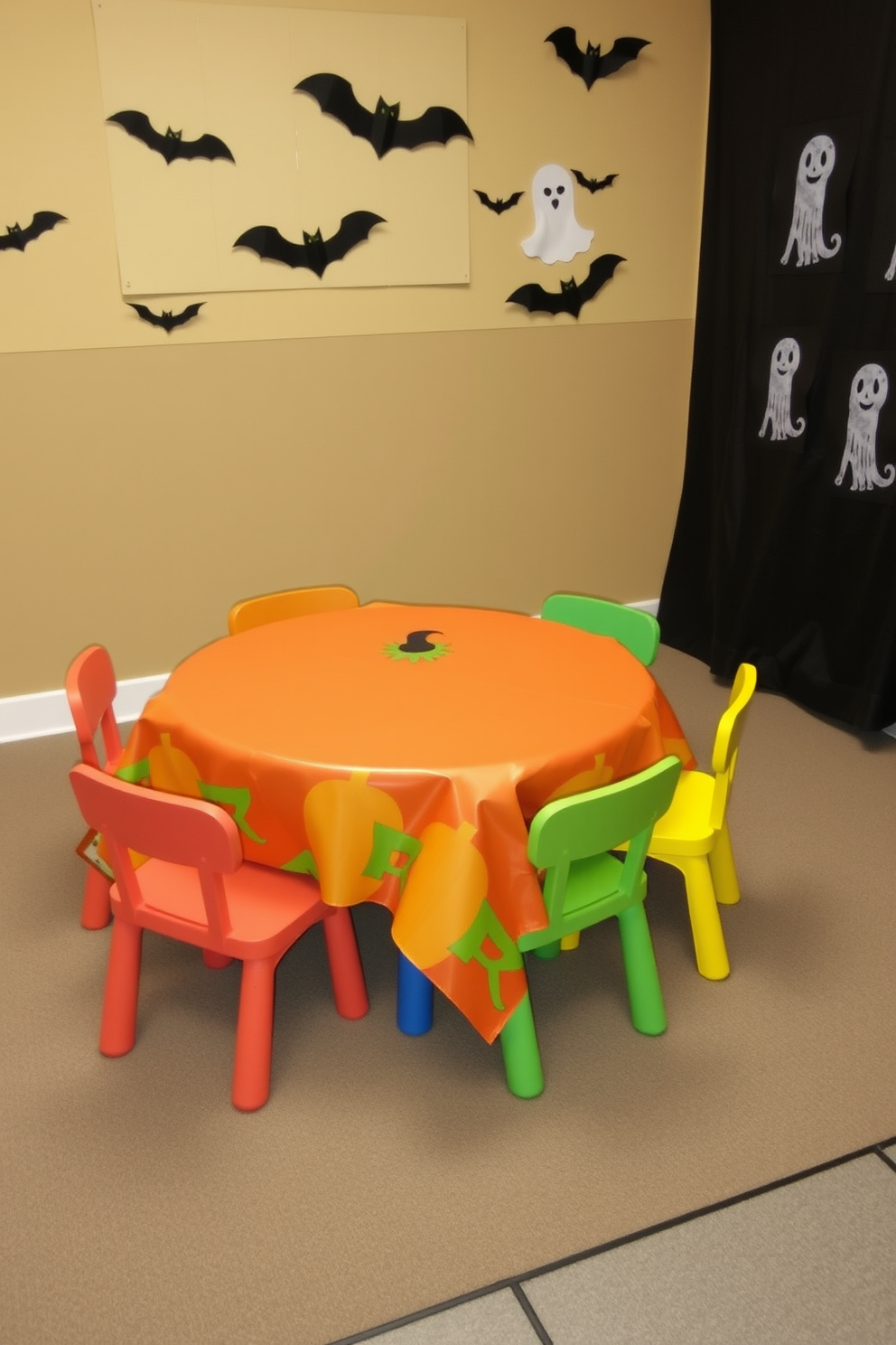 A playful Halloween-themed playroom features a vibrant pumpkin-themed tablecloth draped over a children's play table. Surrounding the table are colorful chairs, and the walls are adorned with cheerful Halloween decorations like paper bats and friendly ghosts.