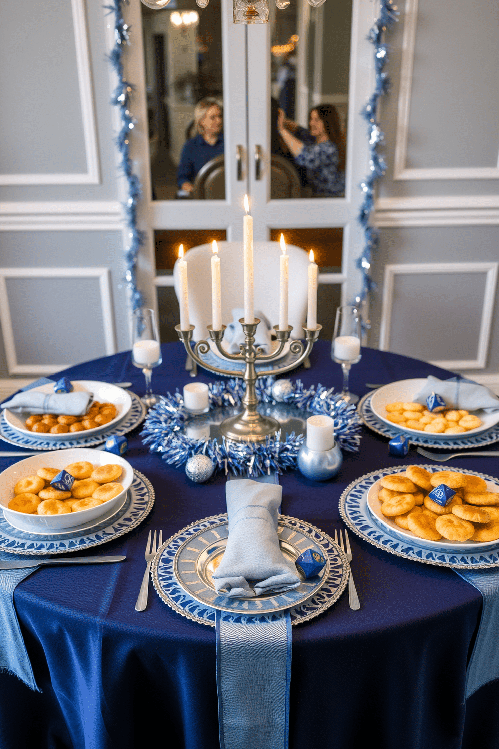 A festive table setting adorned with elegant blue and silver accents. The table is beautifully arranged with themed dishes featuring traditional Hanukkah foods, including latkes and sufganiyot, artfully displayed on decorative platters. Candles flicker in a stylish menorah at the center of the table, surrounded by shimmering garlands and small dreidels. The tablecloth is a rich navy blue, complementing the festive atmosphere and inviting guests to celebrate together.