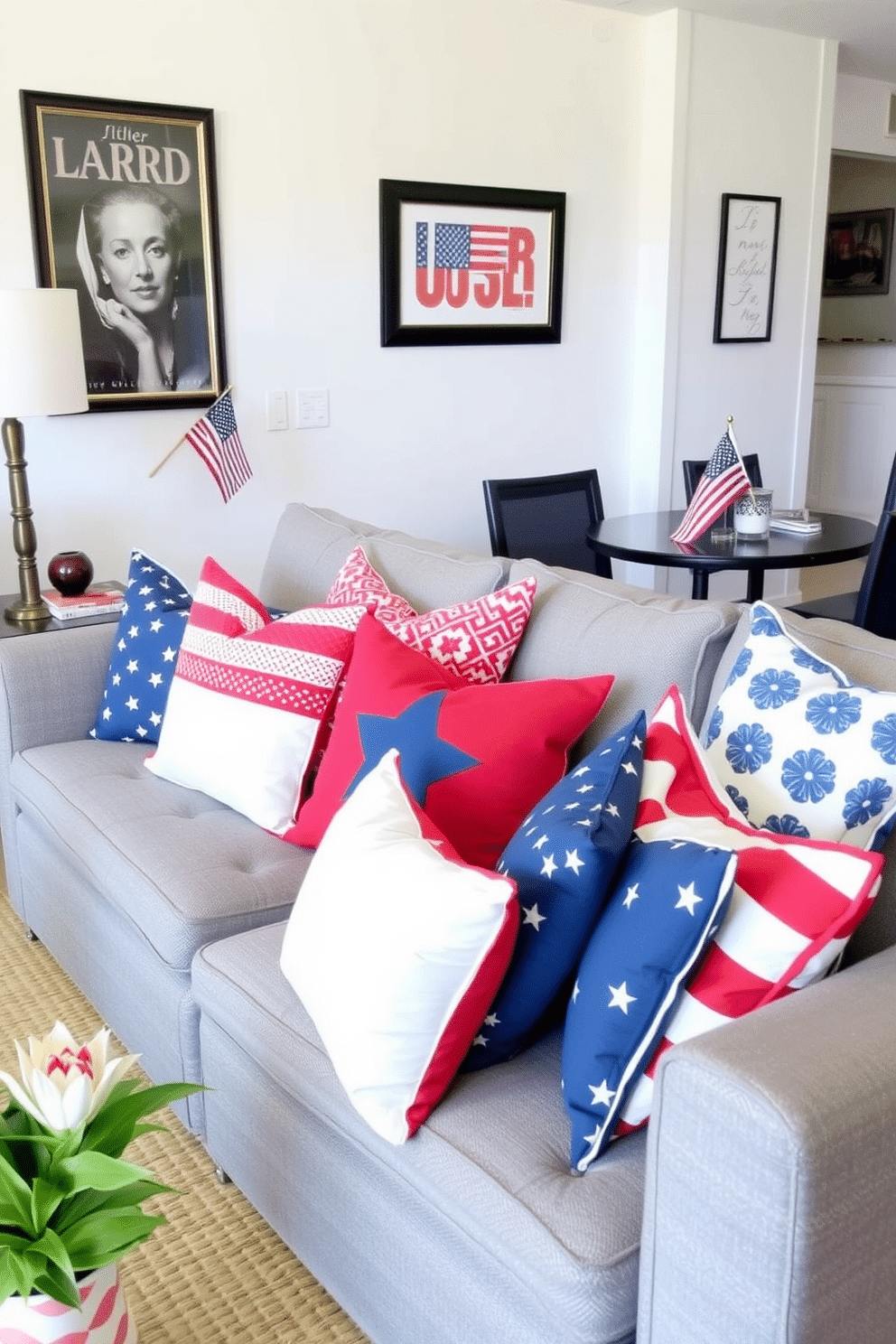 Create a cozy living room setting featuring a collection of red white and blue throw pillows arranged on a stylish gray sofa. The pillows should vary in patterns and textures, adding a festive touch to the space while complementing the surrounding decor. In the background, a cheerful Independence Day theme should be evident through tasteful decorations, such as a small American flag displayed on a side table. The walls are adorned with subtle patriotic artwork, enhancing the overall festive atmosphere of the apartment.