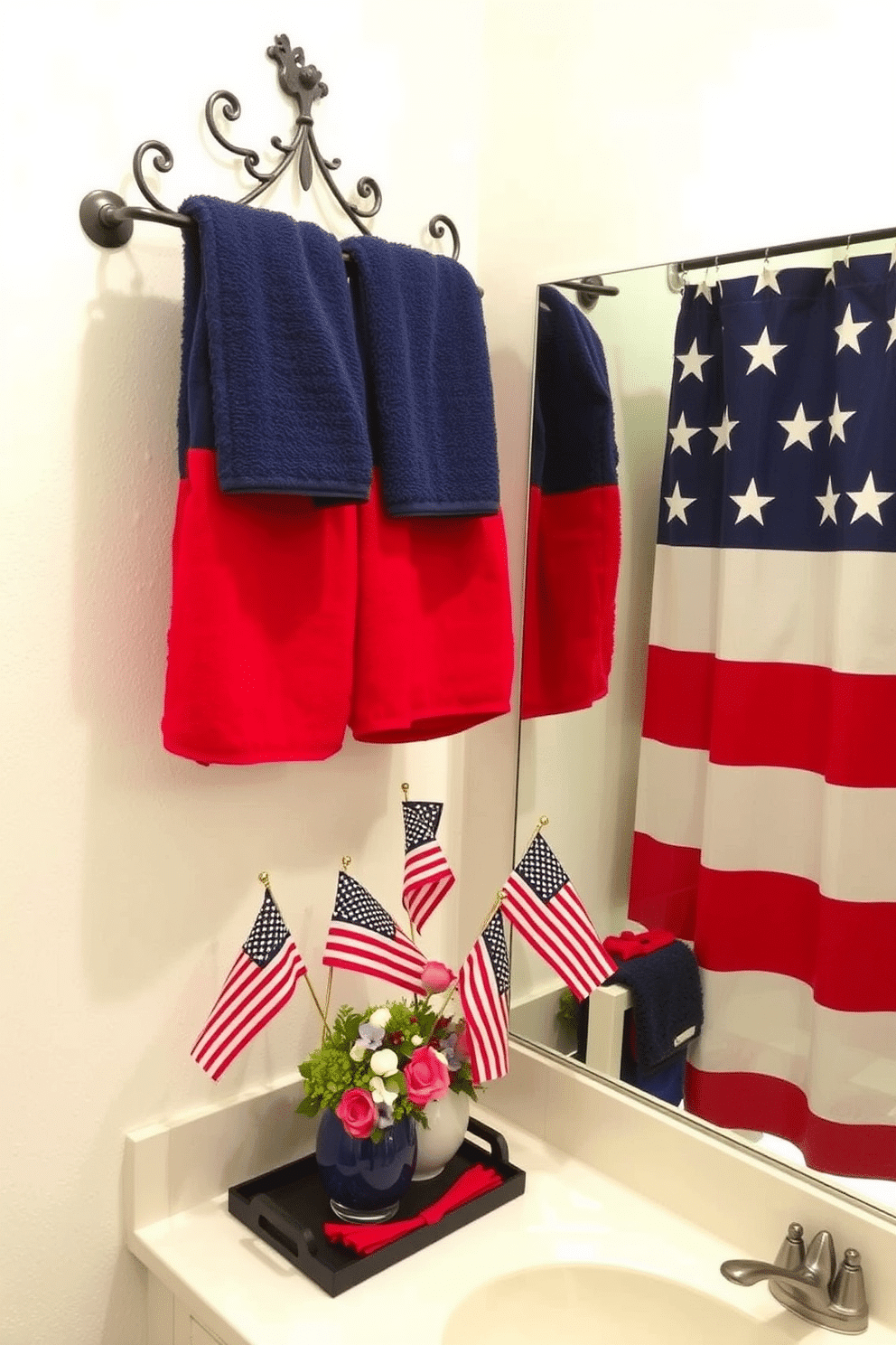 A bathroom featuring patriotic themed bath towels displayed elegantly on a towel rack. The walls are painted in a soft white, and a vibrant red, white, and blue color scheme is incorporated through accessories and decor. The space includes a stylish shower curtain adorned with stars and stripes. A decorative centerpiece on the vanity showcases small flags and seasonal flowers, enhancing the Independence Day spirit.