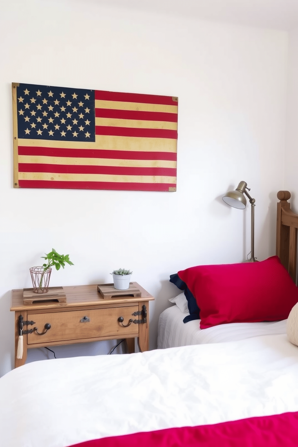 Vintage American flag wall art serves as a striking focal point in a cozy bedroom. The walls are painted in soft white, allowing the vibrant colors of the flag to stand out beautifully. Complementing the artwork, plush red and blue bedding adds a festive touch to the space. A rustic wooden nightstand displays a small potted plant and a vintage lamp, enhancing the patriotic theme.