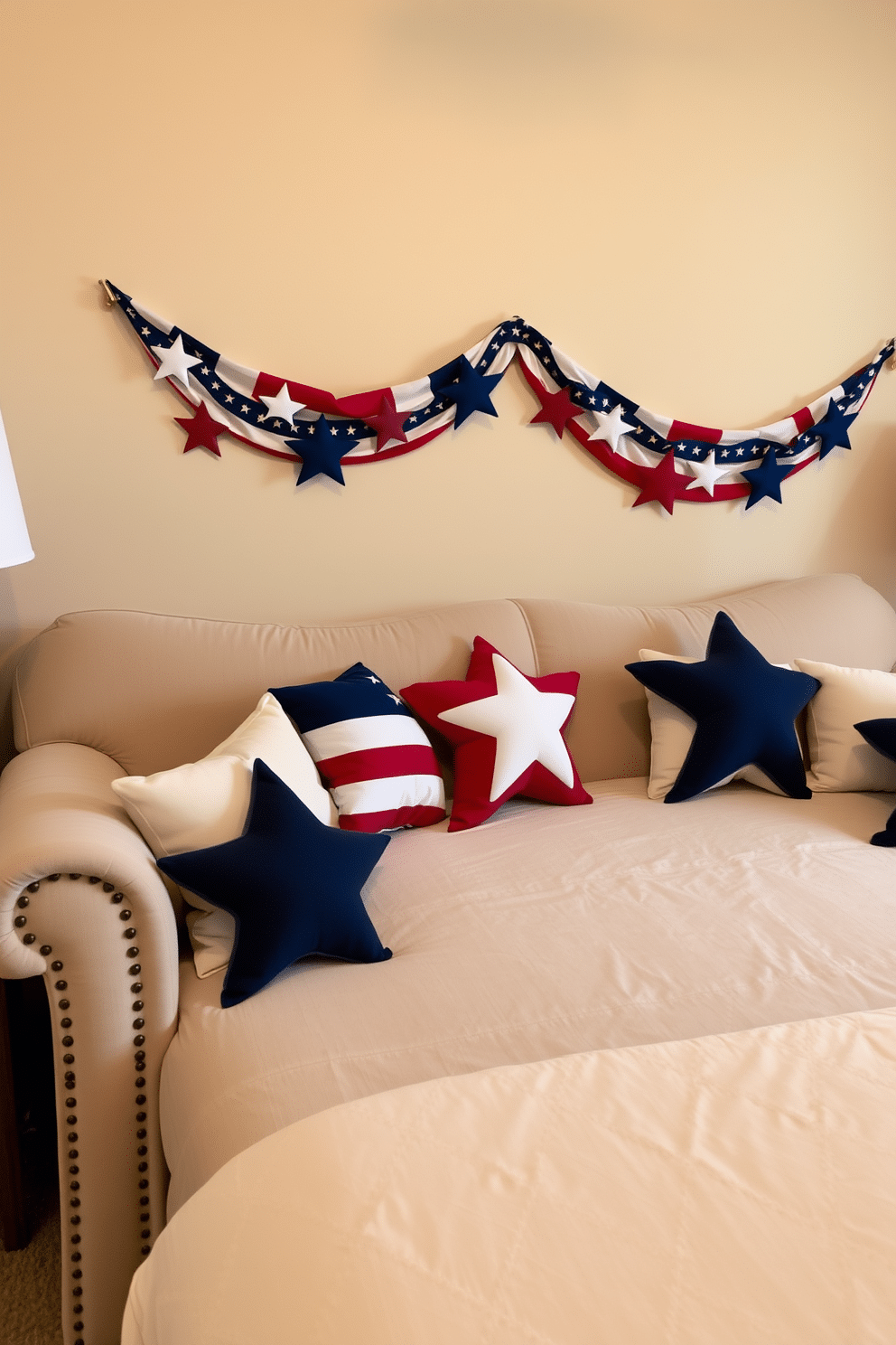 A cozy bedroom setting featuring a plush sofa adorned with decorative star pillows in red, white, and blue. The walls are painted a soft beige, and a festive garland of stars and stripes hangs above the bed, enhancing the Independence Day theme.