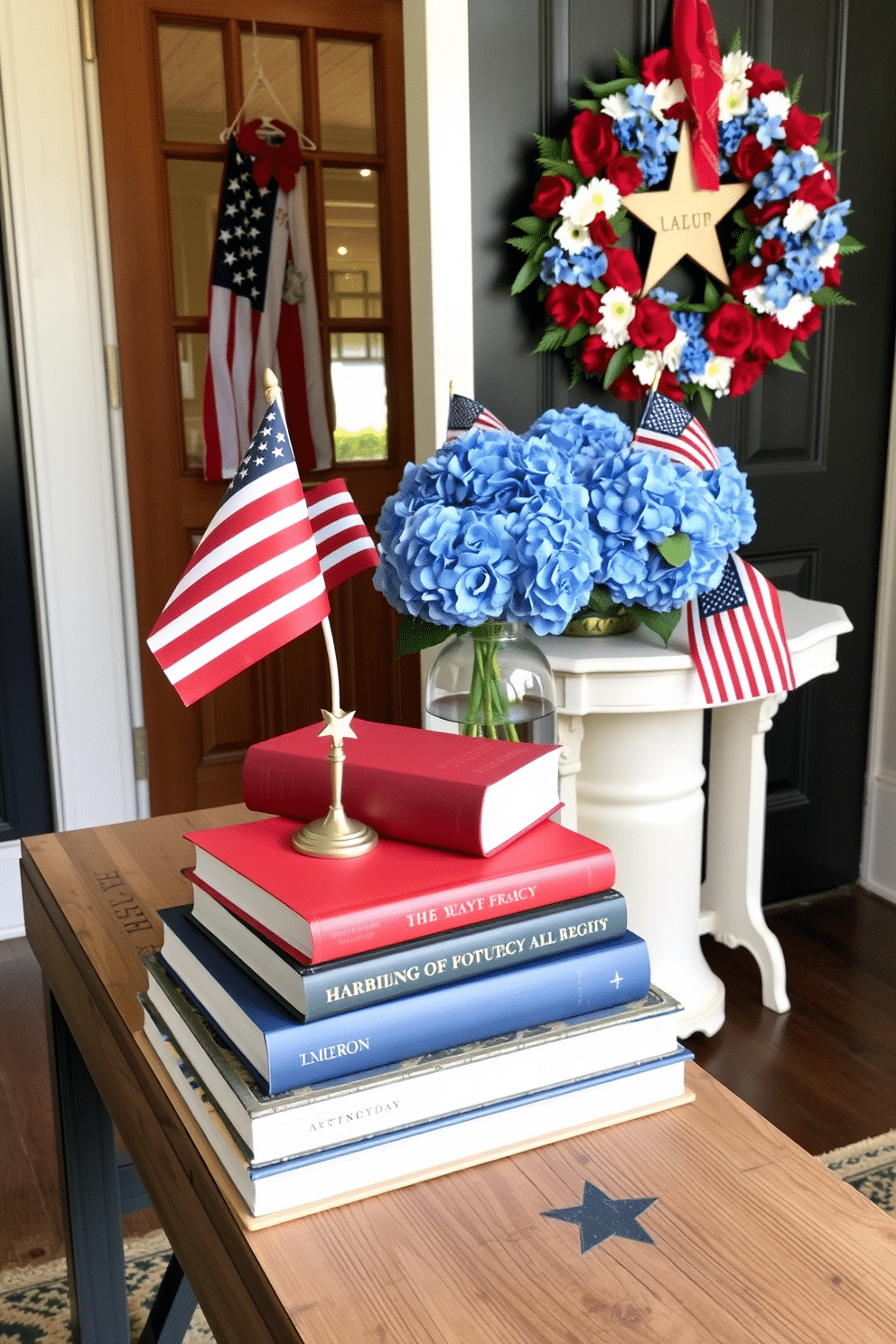 A patriotic themed book stack is arranged on a rustic wooden table. The books are in red, white, and blue covers, topped with a small American flag and a decorative star. The entryway is adorned with festive decorations for Independence Day. A wreath made of red and white flowers hangs on the door, while a table features a vase filled with blue hydrangeas and small flags.