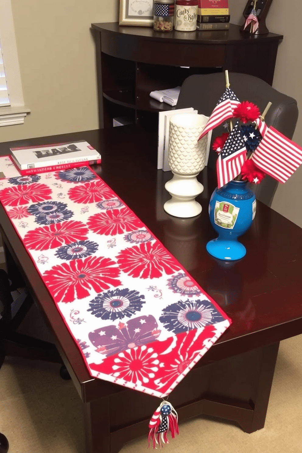 A vibrant table runner adorns the desk, featuring bold red, white, and blue patterns that celebrate Independence Day. Complementing the runner, a collection of decorative items including small flags and themed centerpieces enhance the festive atmosphere of the home office.