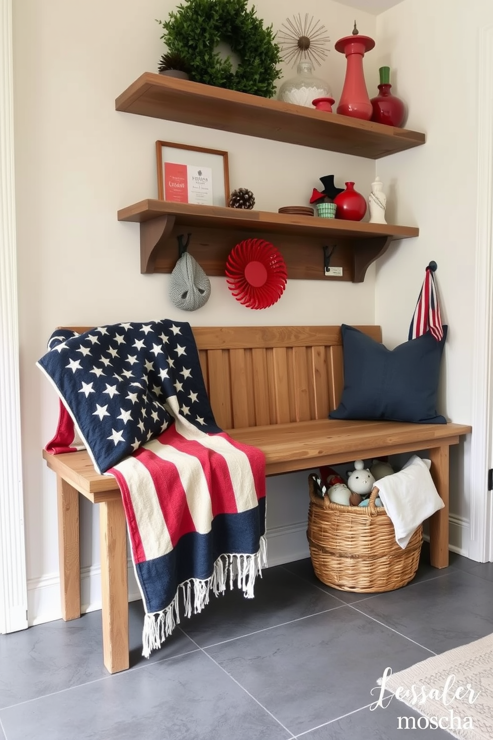 A cozy mudroom adorned with a vintage American flag throw blanket draped over a rustic wooden bench. The walls are painted in a soft cream color, and a collection of red, white, and blue decor pieces are displayed on floating shelves above. The floor features a durable gray tile, ideal for high traffic areas. A woven basket sits next to the bench, filled with seasonal decor and a few patriotic accents for Independence Day celebrations.