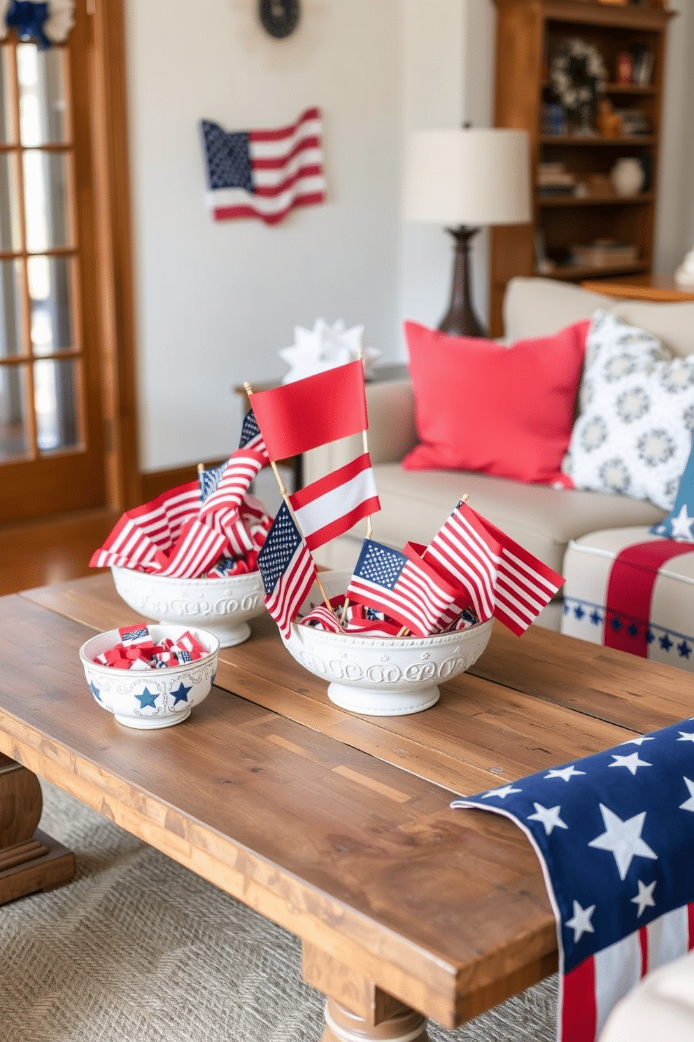 A small living room decorated for Independence Day features decorative bowls filled with vibrant flags in red, white, and blue. The bowls are artfully arranged on a rustic wooden coffee table, surrounded by festive cushions and a patriotic throw blanket.