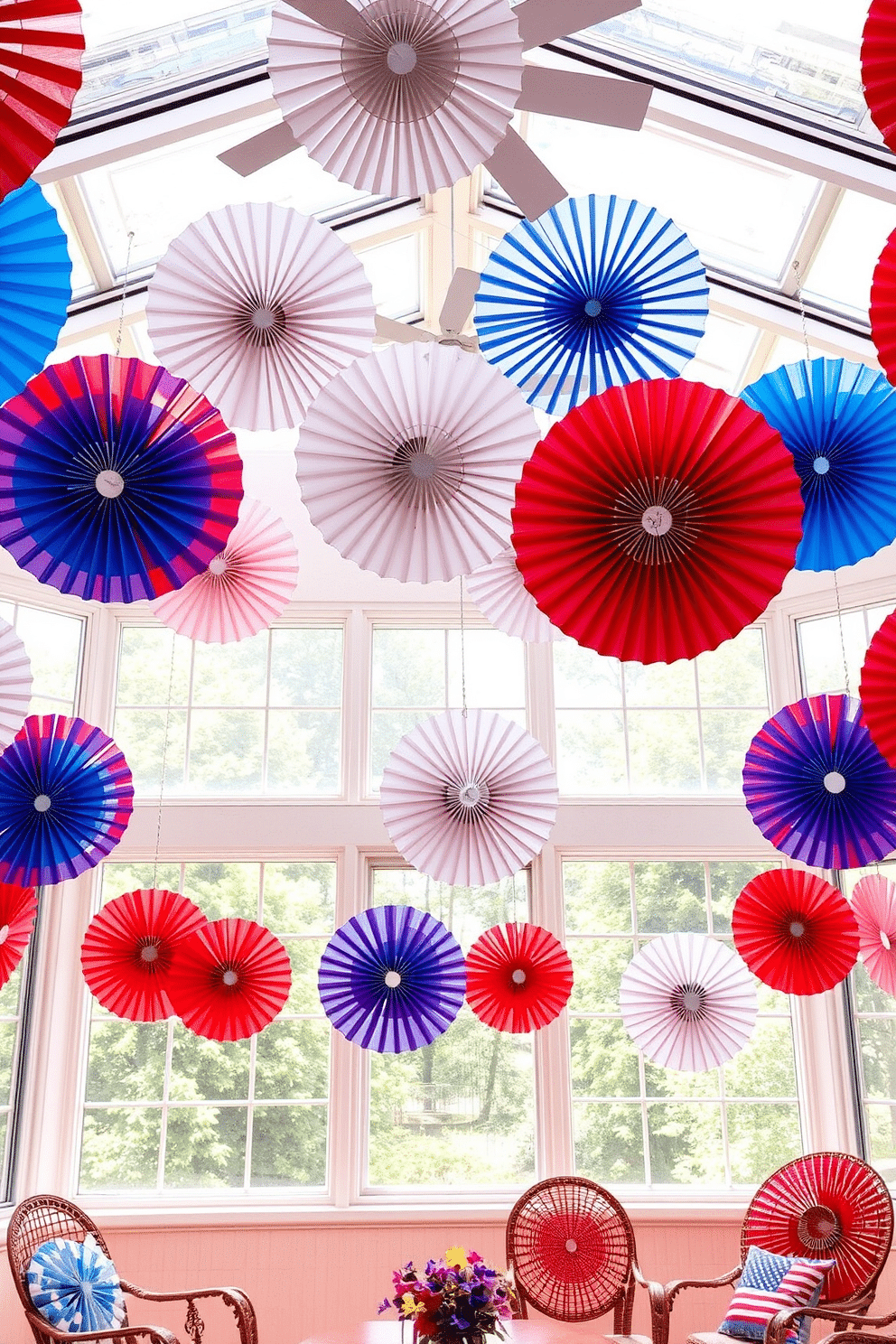 A vibrant sunroom filled with colorful paper fans hanging from the ceiling creates a festive atmosphere. The fans in red, white, and blue complement the natural light streaming through large windows, enhancing the celebratory feel of Independence Day.