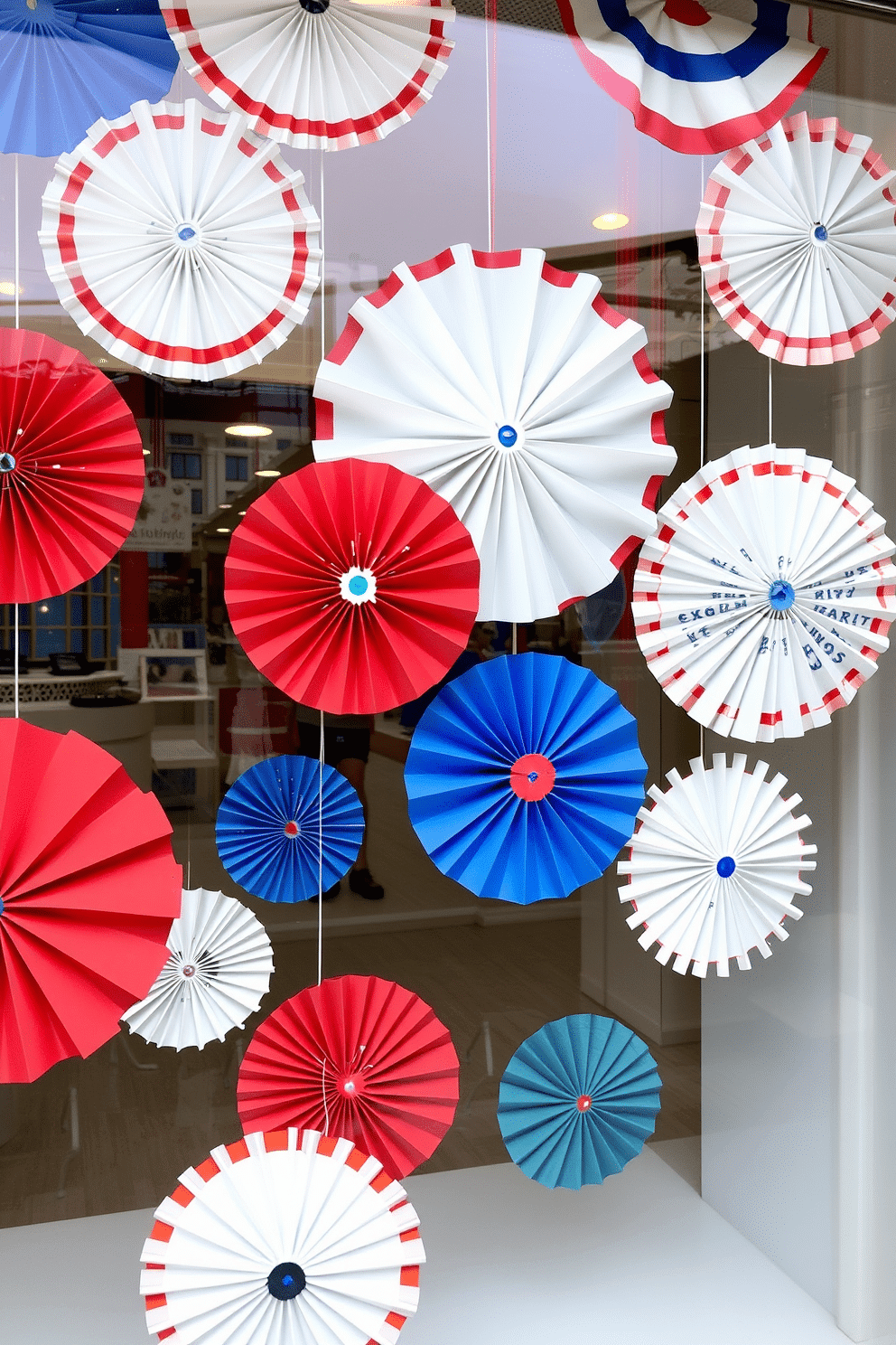 A festive window display for Independence Day featuring hanging red white and blue paper fans. The fans are arranged in a playful pattern, creating a vibrant and patriotic atmosphere.