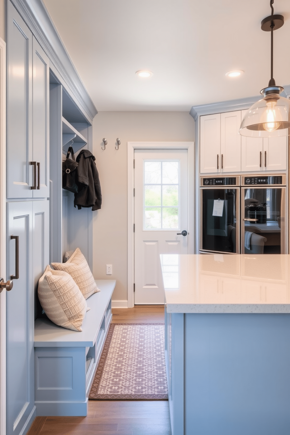 A welcoming mudroom-style entry for a laundry area features built-in cabinetry with ample storage, painted in a soft blue hue to create a calming atmosphere. A bench with plush cushions sits beneath a row of hooks for hanging coats and bags, while a patterned area rug adds warmth to the space. The kitchen laundry room design incorporates sleek, modern appliances seamlessly integrated into custom cabinetry. A spacious countertop provides a functional workspace for folding laundry, complemented by stylish lighting fixtures that enhance the overall aesthetic.