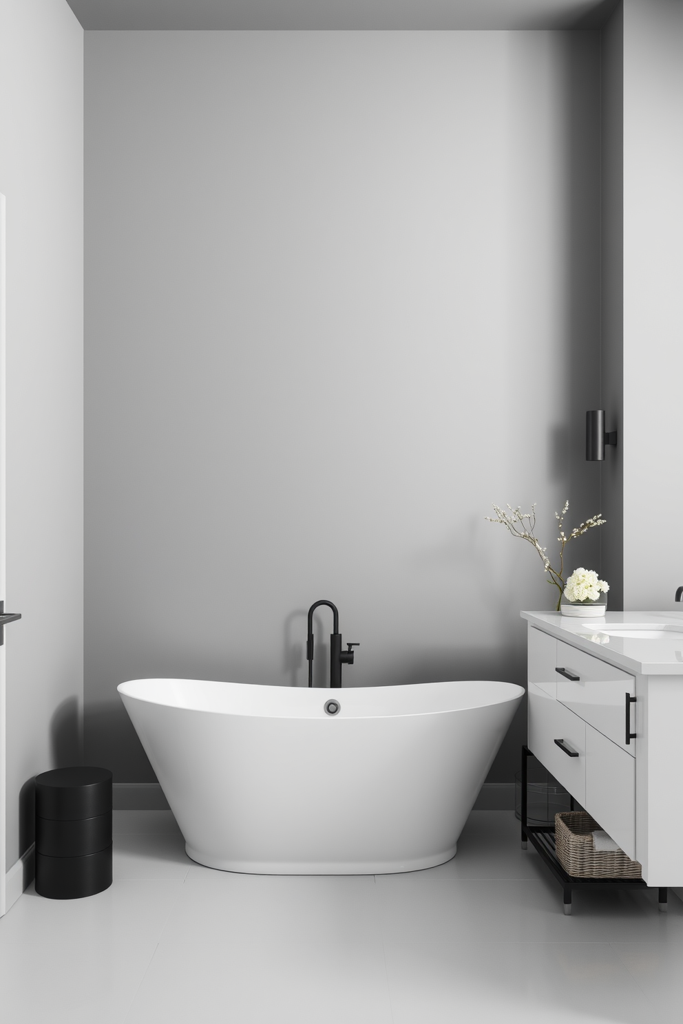 A sophisticated bathroom setting featuring a monochromatic color scheme. The walls are painted in varying shades of gray, creating a seamless and elegant backdrop. A sleek freestanding bathtub sits at the center, surrounded by minimalist decor. The vanity has a clean white finish with a matching countertop, complemented by stylish black fixtures.