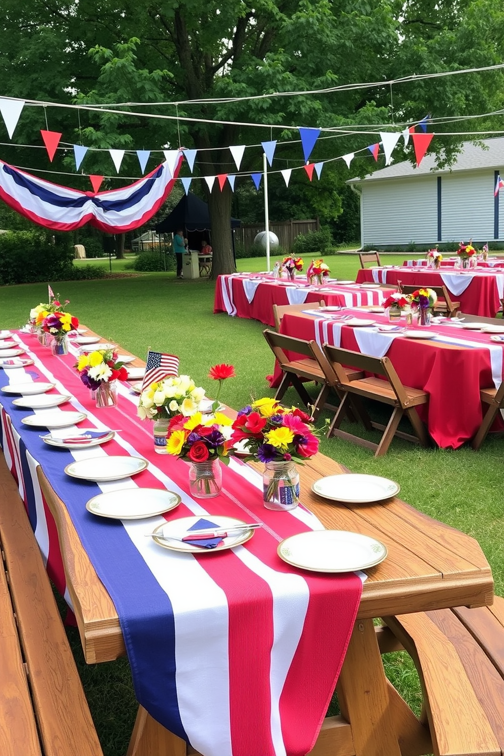 A festive outdoor gathering space adorned with red white and blue tablecloths draping over long wooden tables. The tables are set with matching plates and napkins, while colorful centerpieces featuring seasonal flowers add a touch of charm.