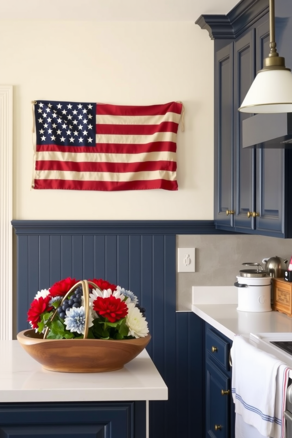 A cozy kitchen setting decorated for Labor Day. The walls are painted in a soft cream color, and the cabinets are a classic navy blue, featuring antique brass hardware. A vintage-style American flag is prominently displayed on the wall, adding a festive touch to the space. The countertops are adorned with seasonal decorations, including a rustic wooden bowl filled with red, white, and blue flowers.