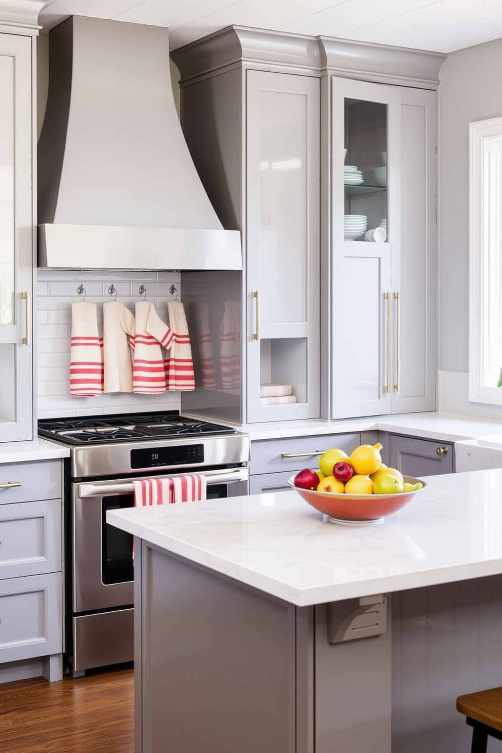 A modern kitchen featuring sleek cabinetry with a glossy finish and an island topped with quartz. The walls are painted in a soft gray, and decorative open shelving displays colorful dishware. Striped towels hang neatly on the oven door, adding a fresh pop of color. A bowl of fresh fruit sits on the island, complementing the overall bright and inviting atmosphere.