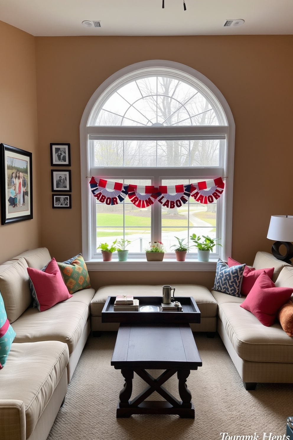 A cozy living room setting with a large window showcasing a view of the outdoors. The walls are painted in warm beige, and a plush sectional sofa is adorned with colorful throw pillows. Framed photos of family gatherings are displayed on a gallery wall, creating a personal touch. A rustic coffee table sits in the center, topped with a decorative tray and a few books for added charm. For Labor Day, the window is decorated with red, white, and blue bunting, creating a festive atmosphere. Potted plants on the windowsill add a touch of greenery and freshness to the space.