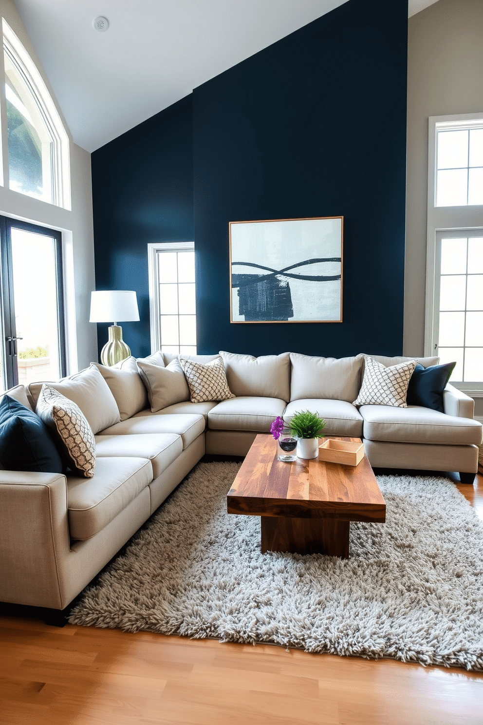 A spacious family room designed in neutral tones features a large sectional sofa adorned with textured throw pillows. The focal point is a bold accent wall painted in a deep navy blue, complemented by modern artwork that adds a touch of sophistication. Natural light floods the room through oversized windows, highlighting a stylish coffee table made of reclaimed wood. A plush area rug anchors the seating arrangement, creating a cozy atmosphere perfect for family gatherings.