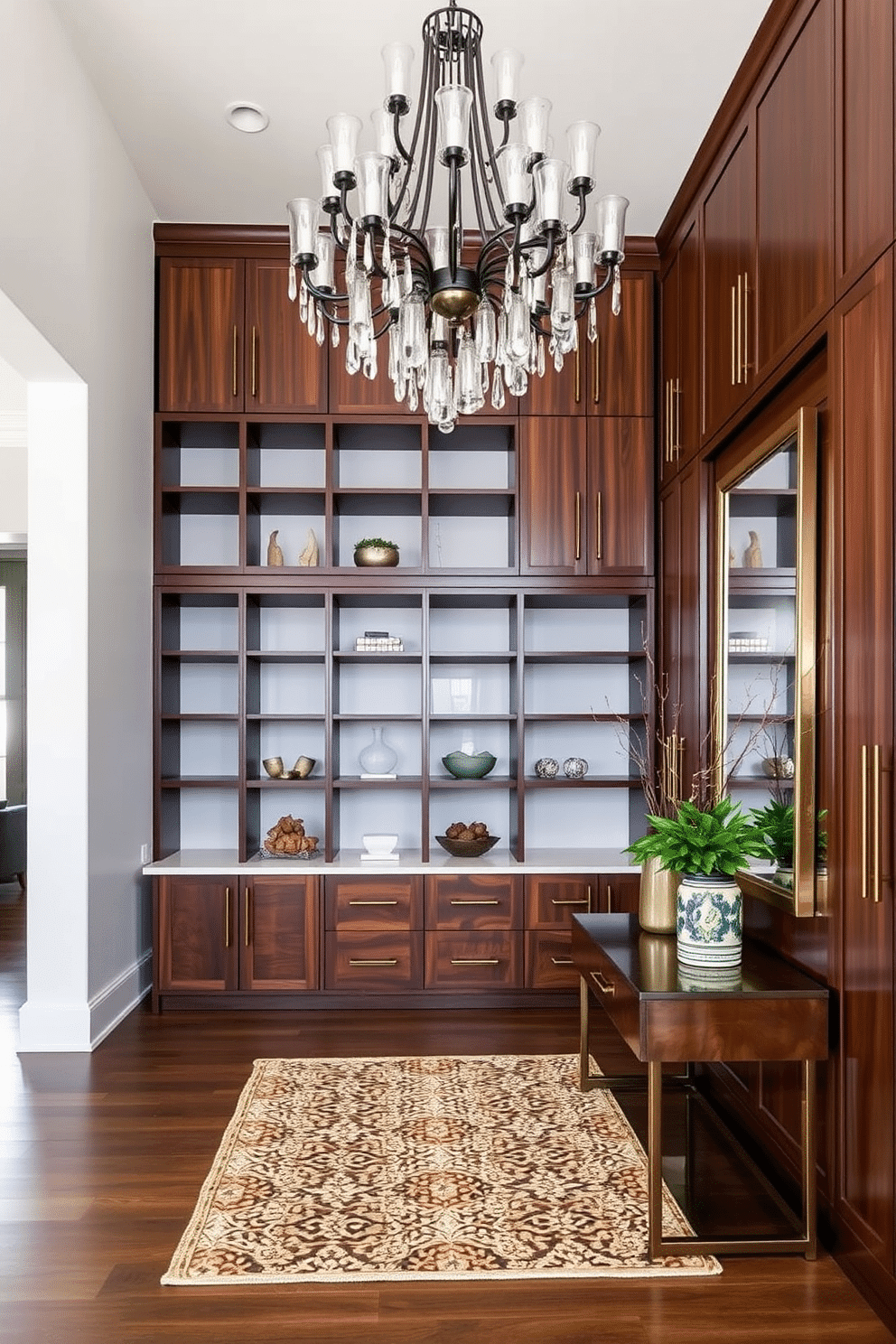 Custom cabinetry for functional storage. The cabinetry features a mix of open shelves and closed compartments, crafted from rich walnut wood with sleek brass handles. Large foyer design ideas. The foyer boasts a grand chandelier hanging from a high ceiling, complemented by a statement console table adorned with decorative accents and a large mirror reflecting the space.