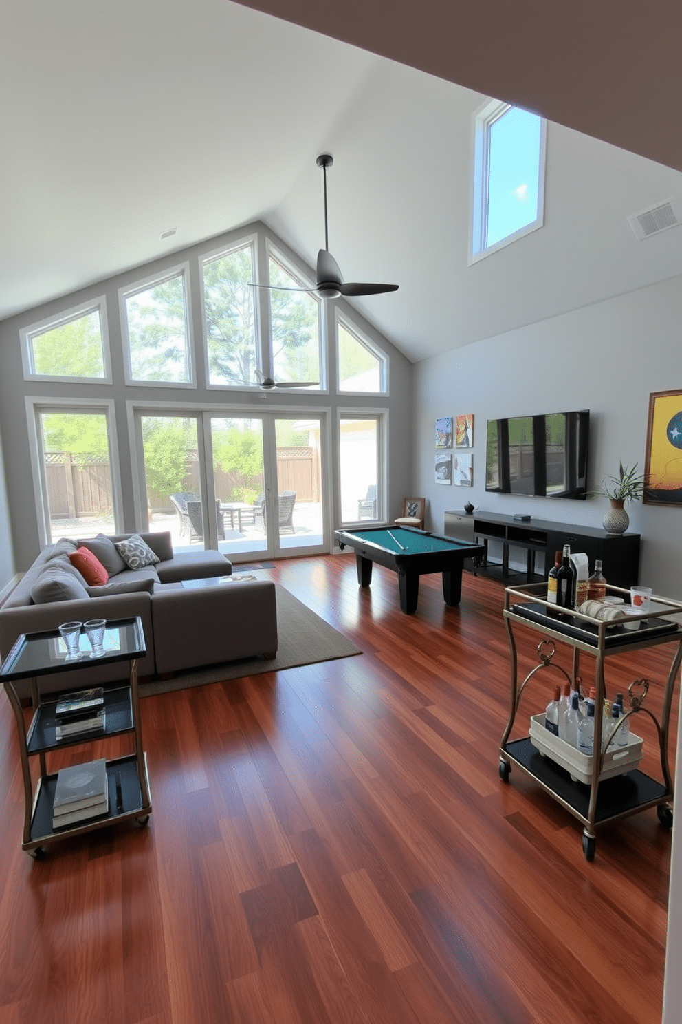 A spacious game room with large windows that open to an outdoor patio, allowing for fresh air breaks and natural light to flood the space. The room features a plush sectional sofa, a pool table in the center, and a large flat-screen TV mounted on the wall, complemented by vibrant artwork. The flooring is a rich hardwood, providing warmth, while the walls are painted in a soft gray to enhance the room's brightness. A stylish bar cart is positioned in one corner, stocked with drinks and snacks, creating an inviting atmosphere for entertaining friends and family.