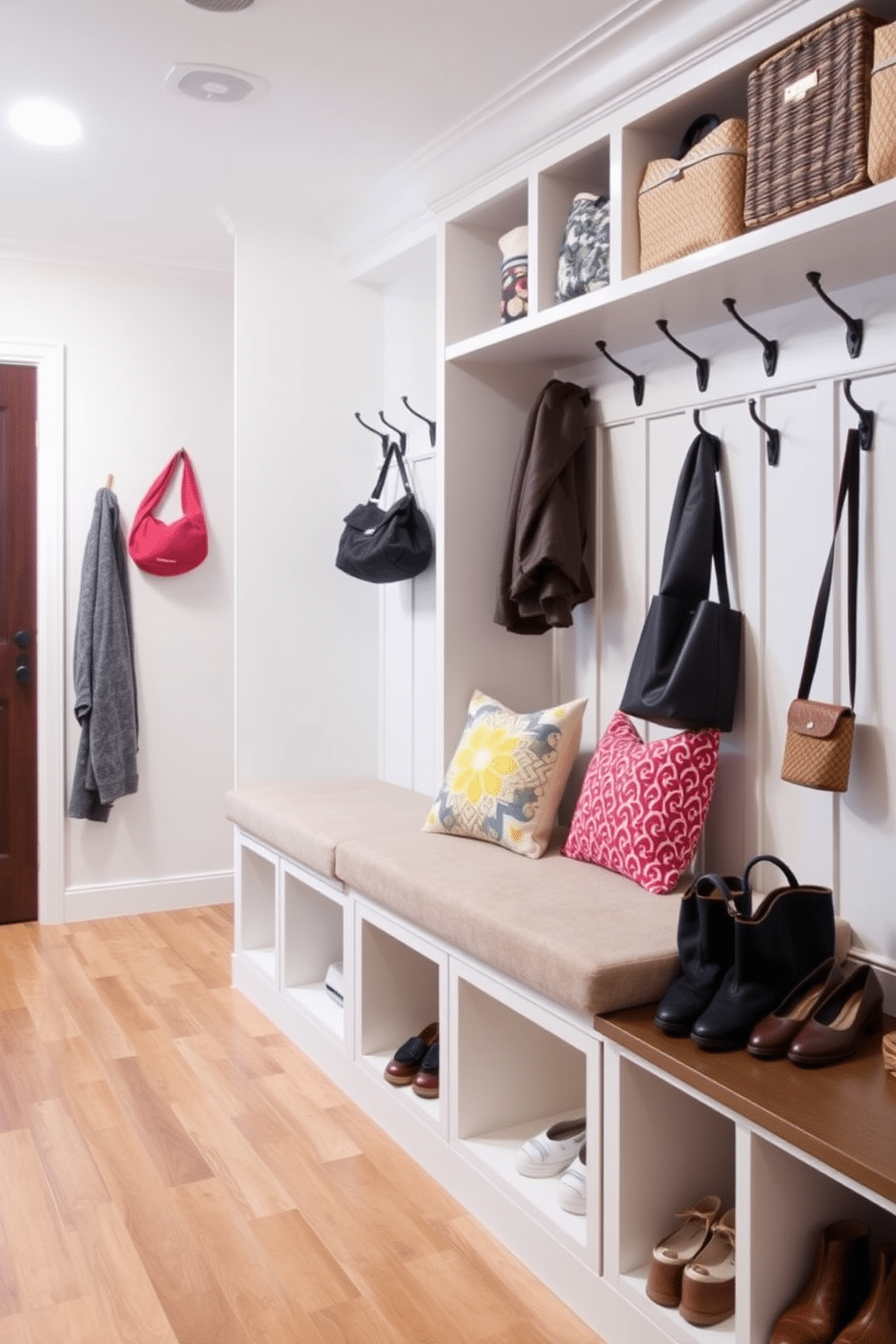 A spacious mudroom features a built-in bench with a plush cushion and colorful pillows, providing a cozy spot to sit and remove shoes. The walls are lined with hooks for coats and bags, while storage cubbies underneath keep the area organized and tidy.