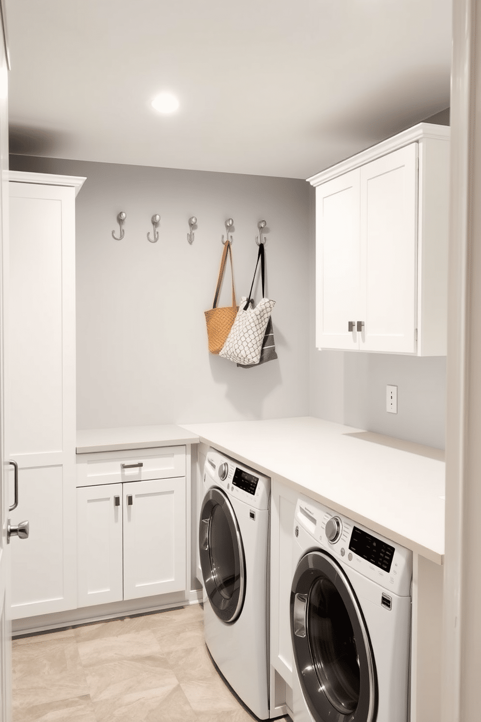 A stylish laundry room in a basement featuring decorative hooks for hanging items. The walls are painted in a soft gray, complemented by sleek white cabinetry and a spacious countertop for folding clothes. Above the countertop, decorative hooks in a brushed nickel finish are mounted, providing a chic solution for hanging items like aprons and bags. The flooring consists of durable, water-resistant tiles in a subtle pattern, enhancing both functionality and aesthetic appeal.