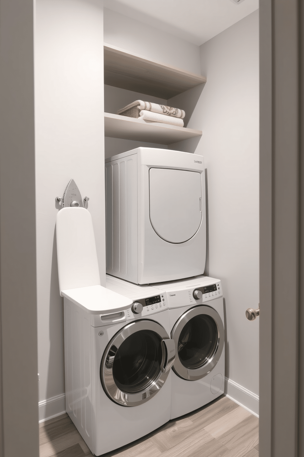 A modern laundry room features a sleek stacked washer and dryer tucked into a corner, maximizing space efficiency. Adjacent to the appliances, a small ironing board area is neatly integrated, with a wall-mounted board that folds down when needed. The walls are painted in a soft, light gray tone, creating a calming atmosphere, while the floor is adorned with durable, water-resistant vinyl planks. Open shelving above the washer and dryer provides storage for laundry essentials, and a decorative basket holds extra towels for convenience.