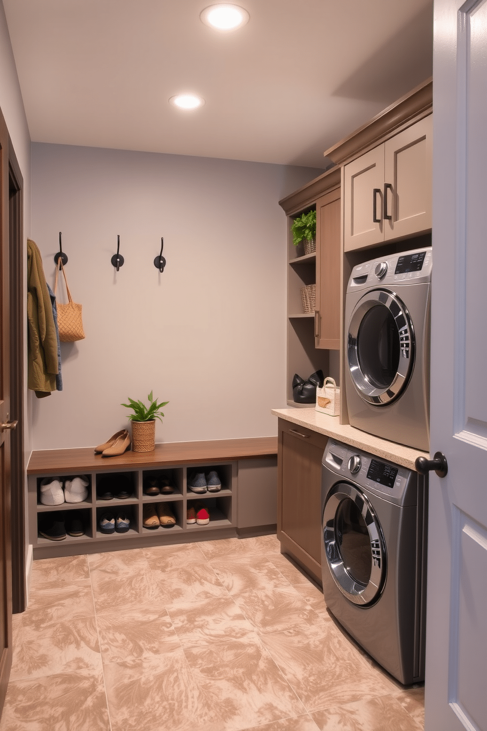 A functional mudroom-laundry hybrid space features a built-in bench with cubbies above for storage of shoes and bags. Adjacent to the bench, a stacked washer and dryer are neatly integrated into cabinetry, with a countertop above for folding clothes. The walls are painted in a soft gray, complemented by a durable tile floor that can withstand moisture. Decorative hooks line the wall for hanging coats, while a small potted plant adds a touch of greenery to the space.