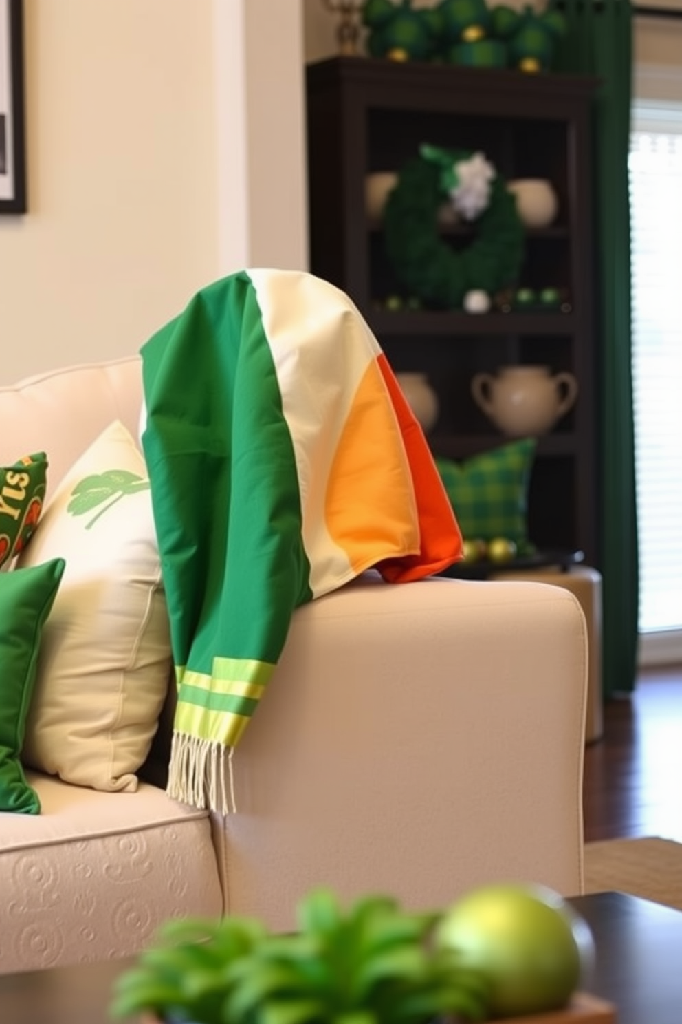 A cozy living room decorated for St. Patrick's Day features a plush sofa adorned with vibrant Irish flag throw blankets draped casually over the armrest. The walls are painted a soft cream, and green and gold accents, such as cushions and decorative pillows, complement the festive atmosphere.