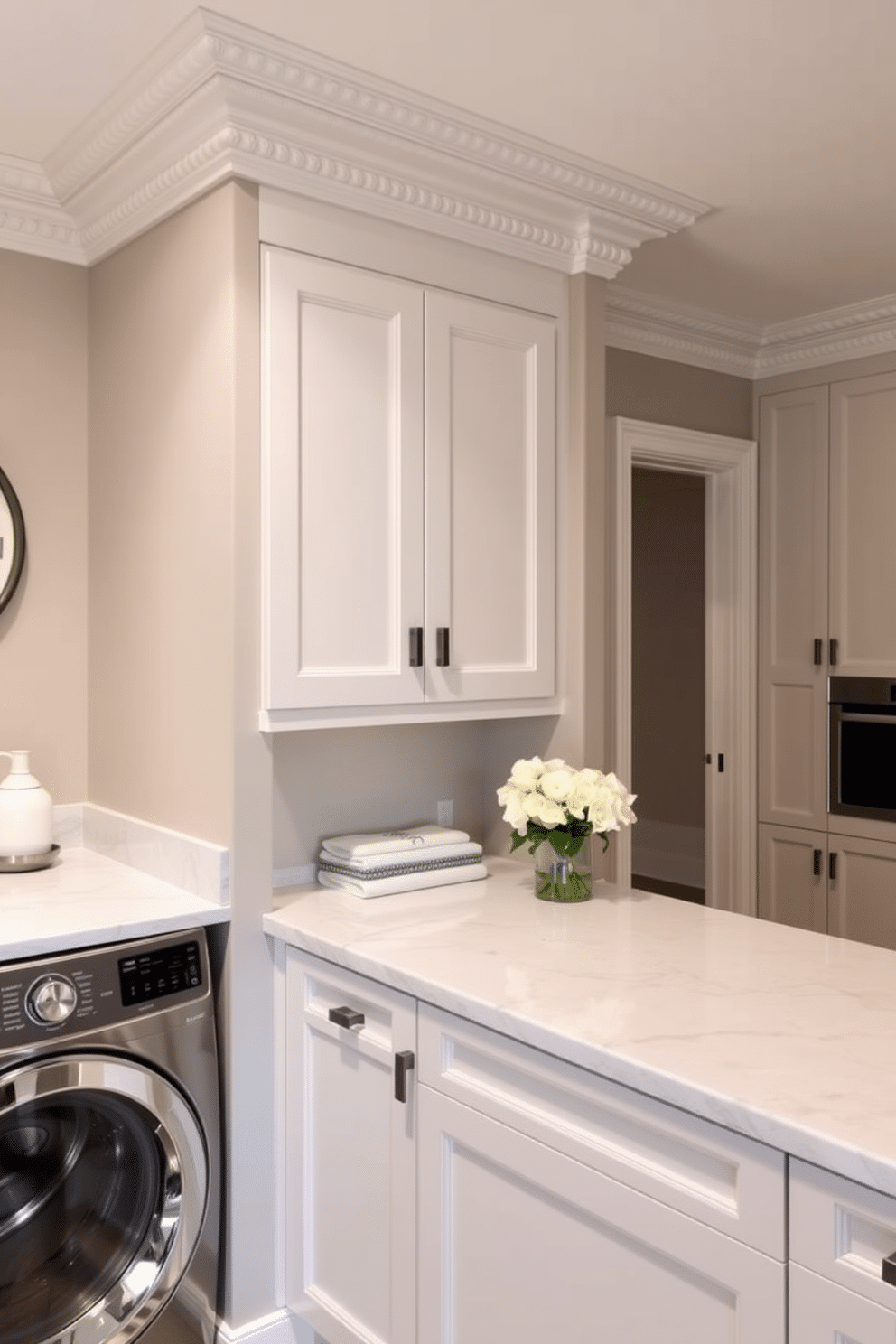 Accent wall with decorative molding details. The wall features intricate crown molding that adds depth and elegance, painted in a soft, muted hue to complement the surrounding decor. Luxury laundry room design ideas. The space includes high-end appliances seamlessly integrated into custom cabinetry, with a stylish countertop for folding clothes and ample storage for laundry essentials.