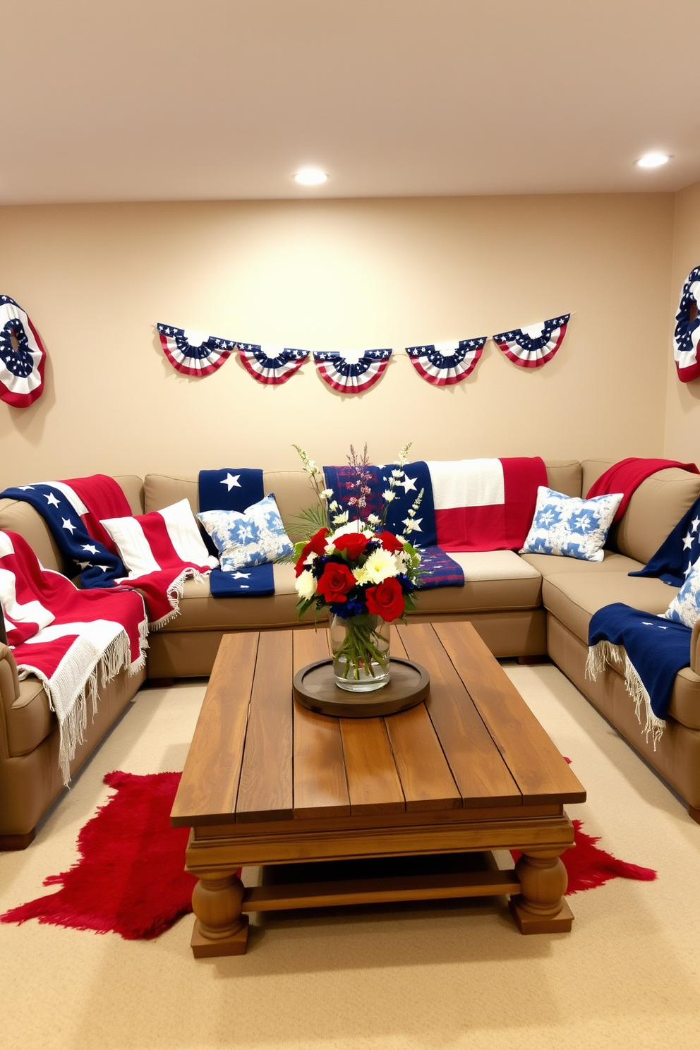 A cozy basement space decorated for Memorial Day. There are several red white and blue throw blankets draped over a large sectional sofa, creating a festive and inviting atmosphere. The walls are painted in a soft beige to enhance the patriotic theme. A rustic wooden coffee table sits in the center, adorned with a centerpiece featuring red white and blue flowers in a glass vase.