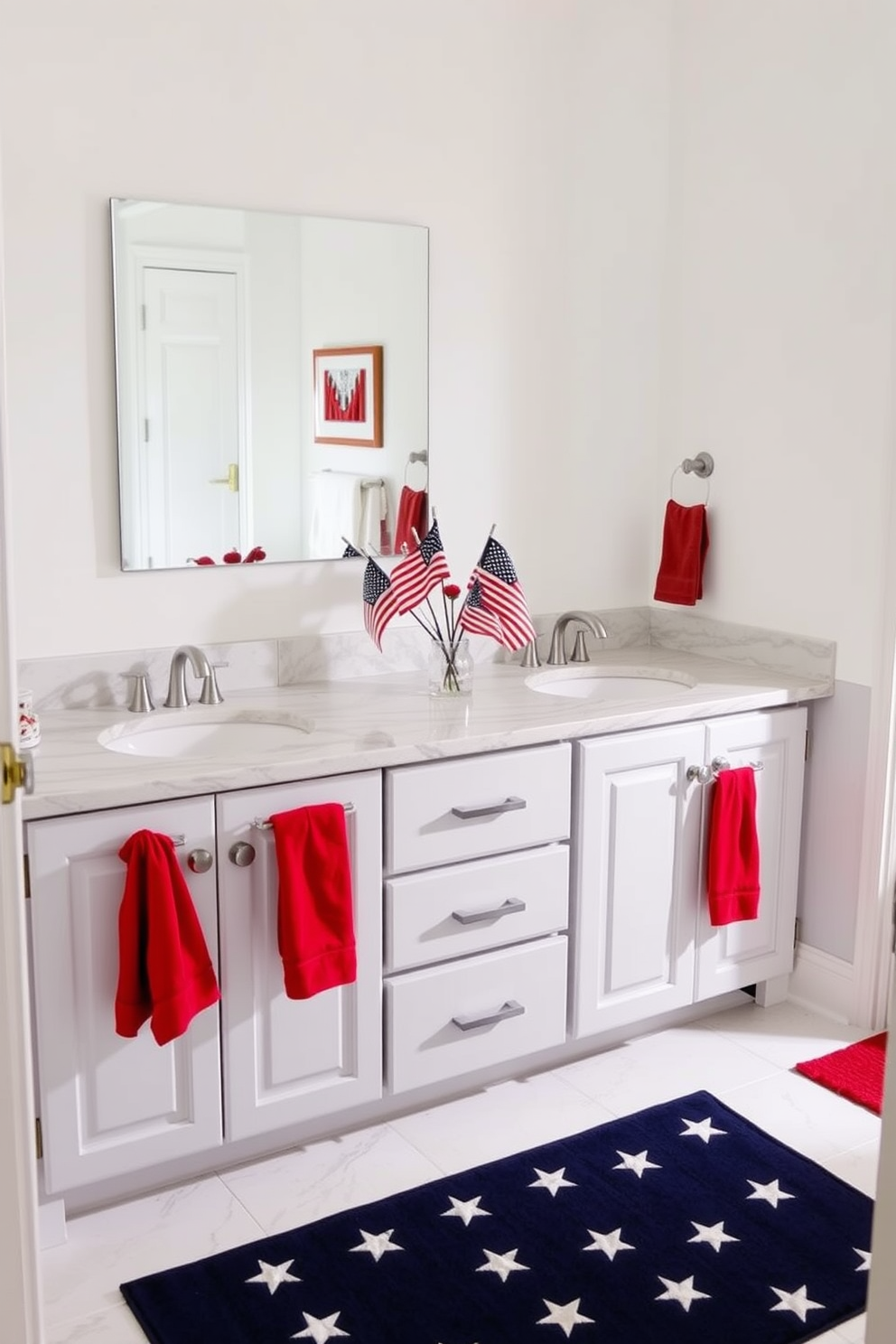 A Memorial Day-themed bathroom decorated with miniature American flags in vases. The flags are placed on the marble countertop of a double sink vanity, adding a patriotic touch to the space. The walls are painted in a crisp white to complement the red, white, and blue color scheme. A navy blue rug with white stars is laid out on the floor, and red hand towels hang from silver hooks.