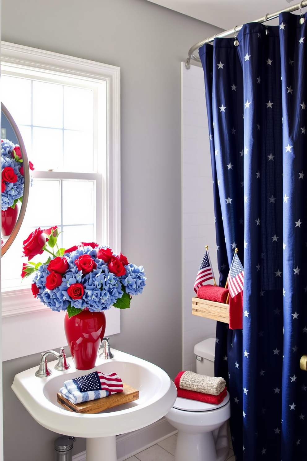 A Memorial Day-inspired bathroom with red and blue floral arrangements. A white pedestal sink is adorned with a vibrant red vase filled with blue hydrangeas and red roses, while a matching arrangement sits on a nearby windowsill, creating a patriotic ambiance. The walls are painted a soft, neutral gray to allow the colors to stand out, and a navy blue shower curtain with white stars adds to the festive theme. Red and blue hand towels are neatly folded on a rustic wooden shelf, and a small American flag is placed in a corner, subtly enhancing the holiday spirit.