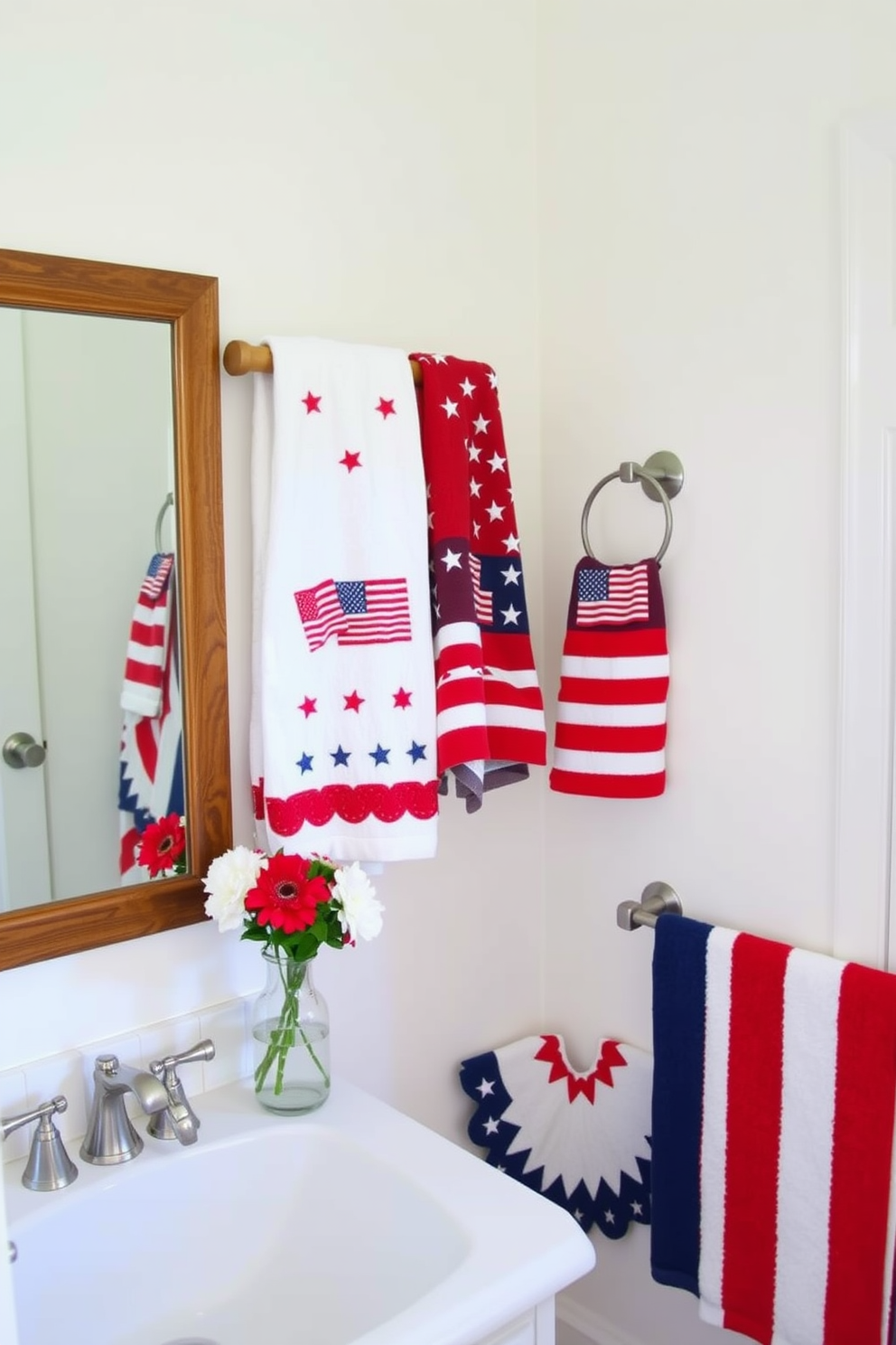 A bright and inviting bathroom adorned with Memorial Day-themed towels. The towels feature patriotic colors of red, white, and blue, with stars and stripes patterns hanging neatly on a wooden towel rack. The bathroom walls are painted in a soft white, providing a clean backdrop for the festive decor. A small vase with fresh flowers in red, white, and blue sits on the vanity, complementing the seasonal towels and adding a touch of elegance to the space.