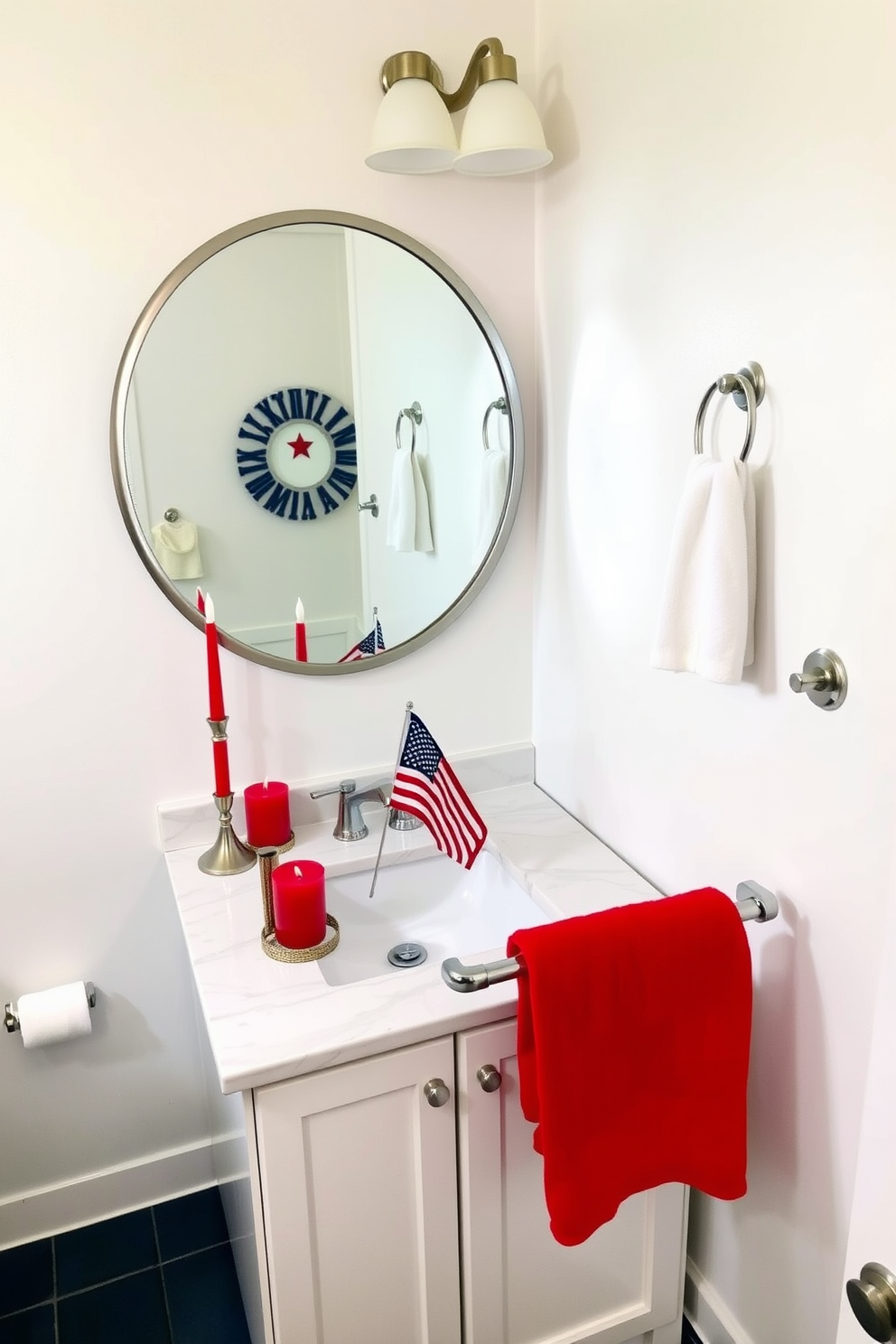 A festive bathroom decorated for Memorial Day. Red and blue candles are placed on a white marble vanity, adding a patriotic touch. The vanity features a single sink with a large, round mirror above it, framed in brushed nickel. The walls are painted a crisp white, and the floor is covered in navy blue tiles. A small American flag stands in a decorative holder on the countertop, and a red towel is neatly folded on a chrome towel rack.