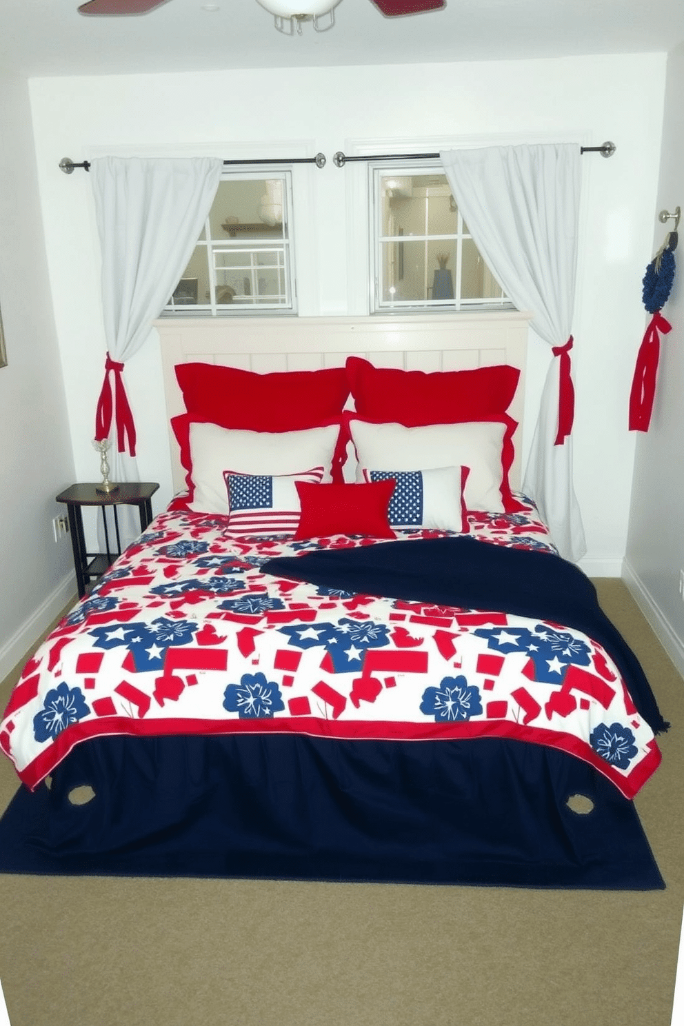 A cozy bedroom decorated for Memorial Day. The bed features a red, white, and blue bedspread with a bold, patriotic pattern, complemented by matching pillows in solid colors. The walls are painted a soft white, allowing the vibrant colors of the bedspread to stand out. A navy blue rug under the bed adds a touch of elegance, while white curtains with red tiebacks frame the windows, completing the festive look.