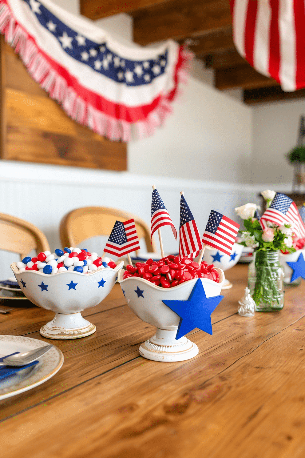 A rustic wooden table is adorned with decorative bowls filled with patriotic candies in red, white, and blue. Each bowl is intricately designed with star patterns, complementing the festive theme and adding a touch of charm to the Memorial Day decor. In the background, an American flag-themed garland hangs above the table, enhancing the patriotic ambiance. The table is set with vintage plates and cutlery, while small American flags are placed in mason jars filled with fresh flowers, completing the Memorial Day decorating ideas.