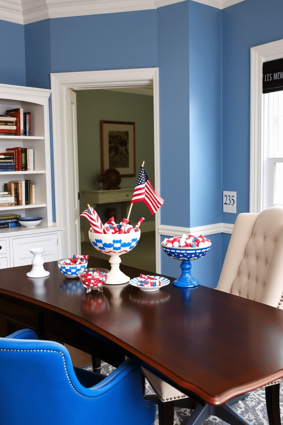 A stylish home office designed for Memorial Day celebrations. The desk is adorned with decorative bowls filled with red white and blue patriotic candy, creating a festive atmosphere. The walls are painted in a soft blue hue, complemented by white trim. A comfortable chair sits beside the desk, and a small flag is displayed on the bookshelf to enhance the patriotic theme.