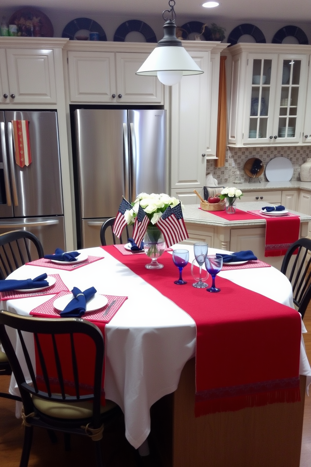 A Memorial Day kitchen is adorned with red, white, and blue table linens. The table is set with a white tablecloth, red placemats, and blue napkins, creating a patriotic theme. A centerpiece features a vase filled with white flowers and small American flags. The kitchen island is decorated with a red runner, white dishes, and blue glassware, all enhancing the festive atmosphere.