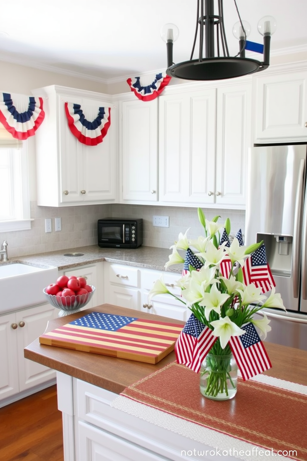 A kitchen adorned for Memorial Day. On the countertop, there is a wooden cutting board designed like the American flag, prominently displayed near a bowl of fresh red apples. Above the countertop, an arrangement of red, white, and blue bunting adds a festive touch. The kitchen island is decorated with a vase of white lilies and small American flags, creating a patriotic centerpiece.