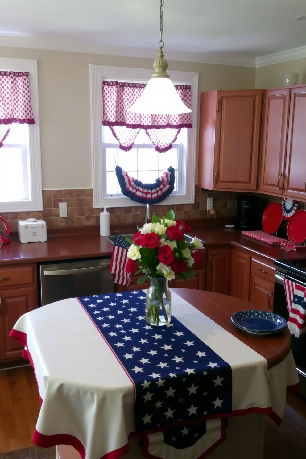 A cozy kitchen decorated for Memorial Day celebrations. Red and blue patterned curtains hang from the windows, complementing the patriotic theme. The kitchen island is adorned with a festive tablecloth featuring stars and stripes, and a vase of fresh flowers sits at the center. Red, white, and blue bunting is draped along the cabinets, and a display of colorful plates and napkins is set up on the countertops.