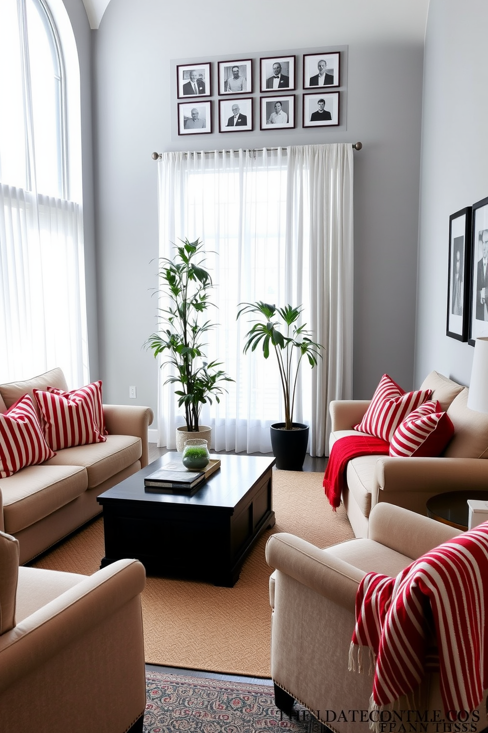 A cozy living room setting with red and white striped cushions adorning a plush beige sofa. A large window with sheer white curtains allows natural light to flood the room, highlighting the dark wood coffee table in the center. In the corner, a tall potted plant adds a touch of greenery, while a red and white striped throw blanket is draped over an armchair. The walls are painted a soft grey, and a series of framed black-and-white photographs hang above the sofa, creating a sophisticated yet inviting atmosphere.