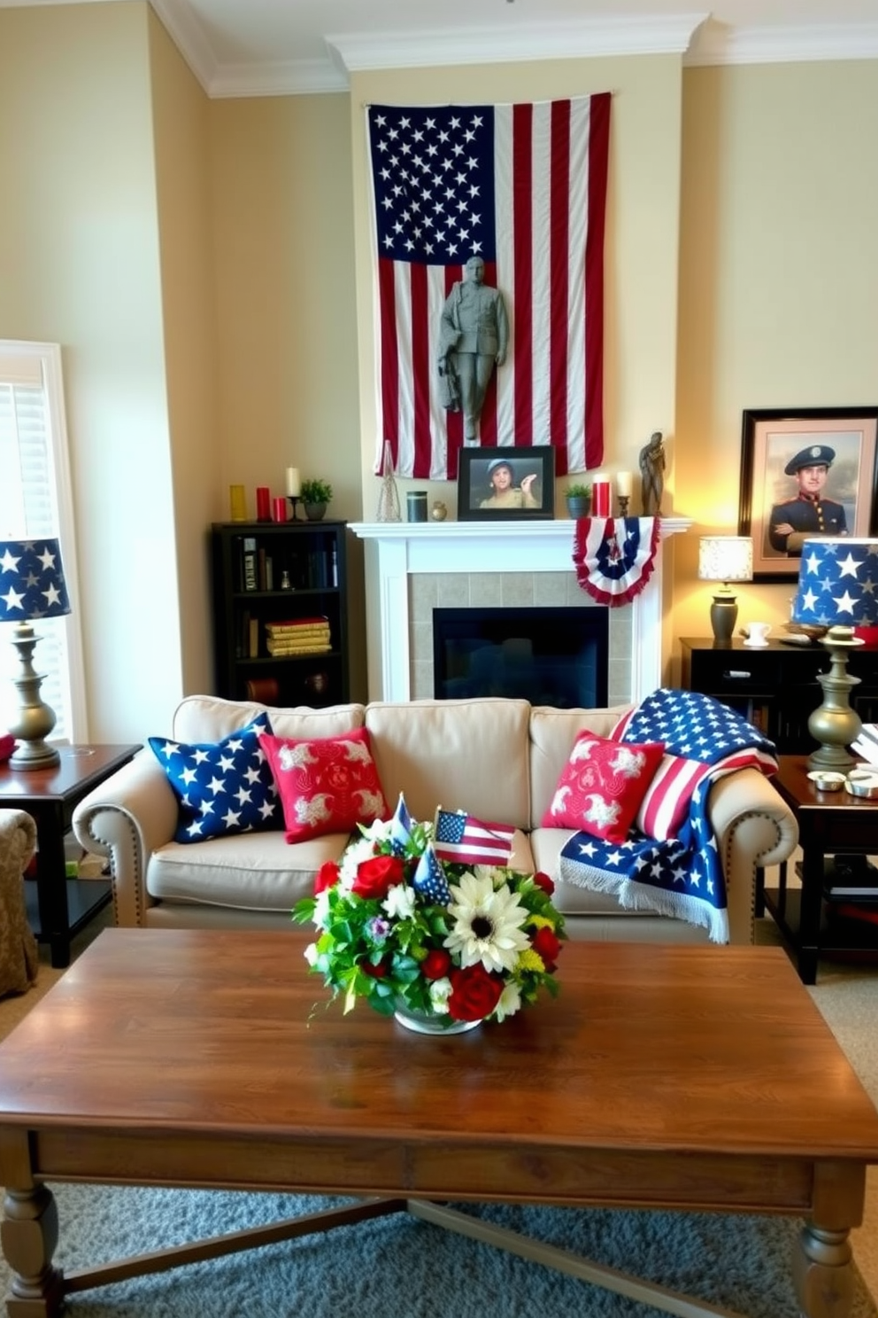 A cozy living room adorned with Memorial Day decorations. The walls are painted a soft beige, and a large American flag hangs prominently above the fireplace. On the mantel, there are red, white, and blue candles and a framed photo of a soldier. The sofa is covered with patriotic-themed throw pillows, and a woven American flag blanket is draped over the back. A coffee table in front of the sofa displays a centerpiece of fresh flowers in patriotic colors. The room is illuminated by a combination of natural light from a large window and soft lighting from table lamps with star-spangled shades.